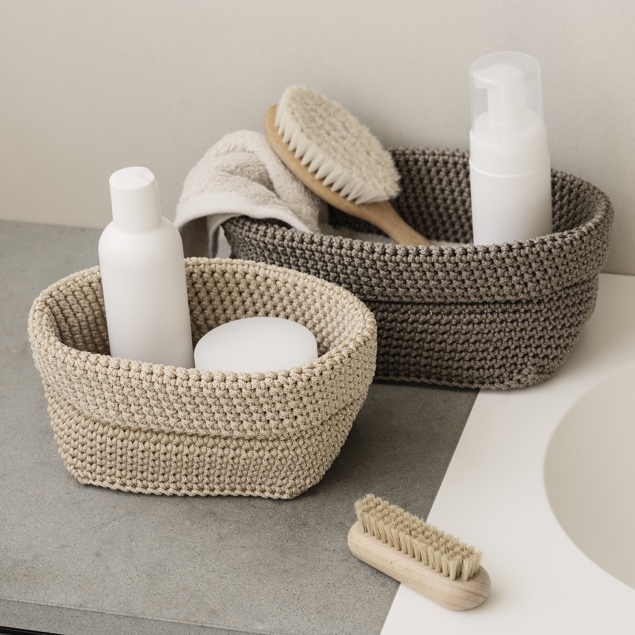 Toiletries organized in knitted storage baskets on a bathroom counter