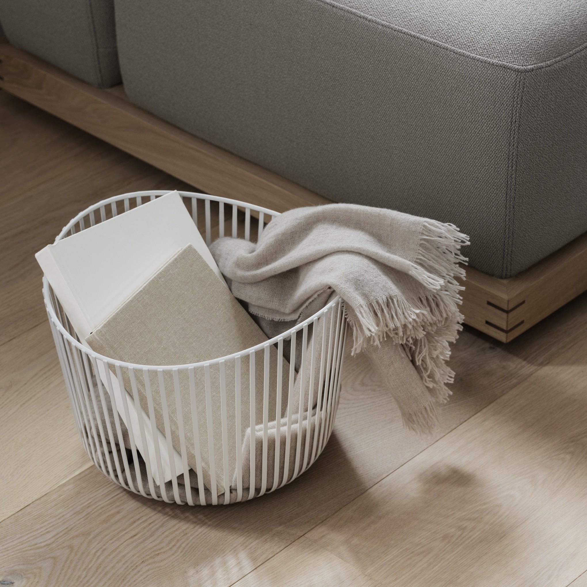 Modern living room with wire basket organizer containing books and a blanket