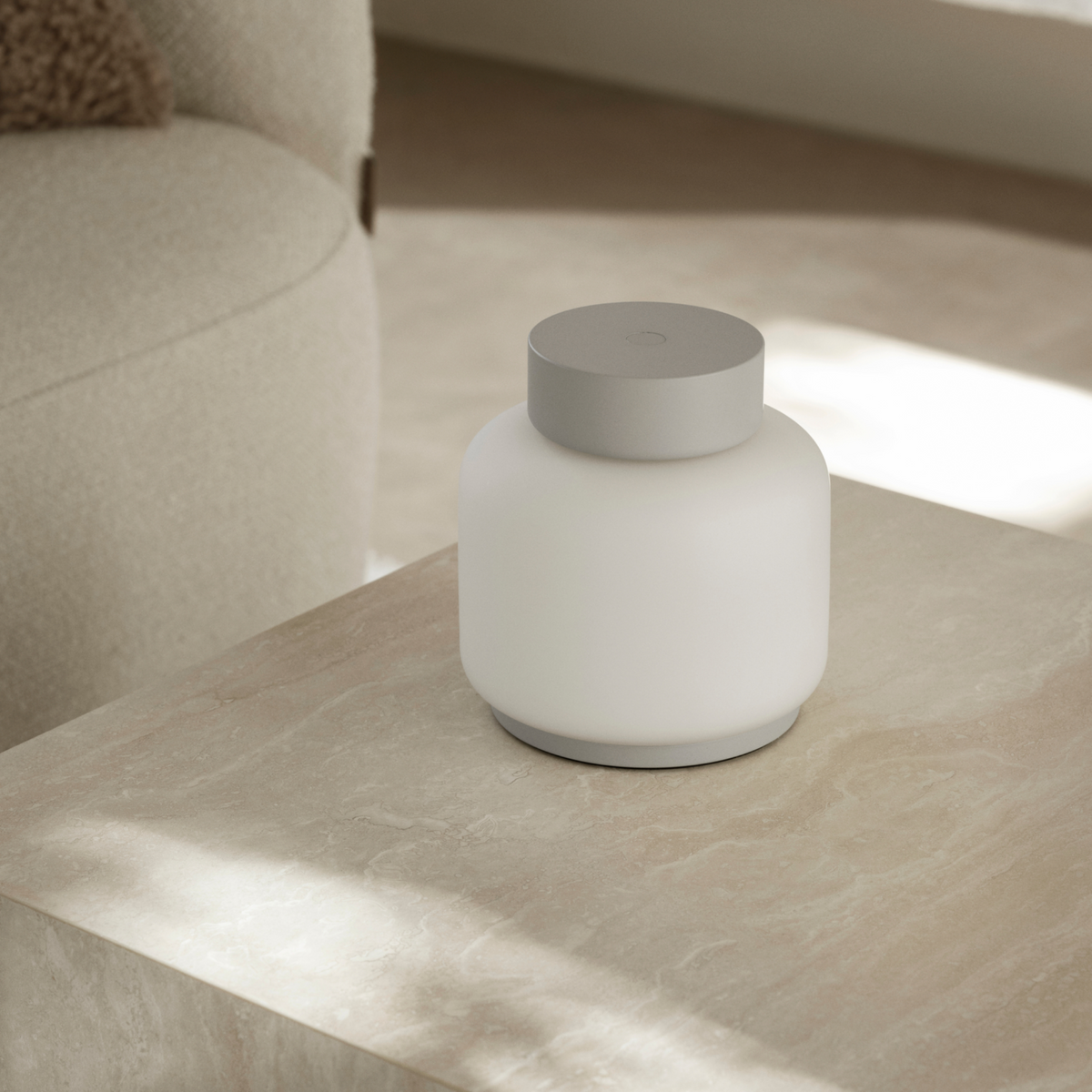 FAWN Lantern placed on a neutral coffee table indoors with a neutral chair in the background.