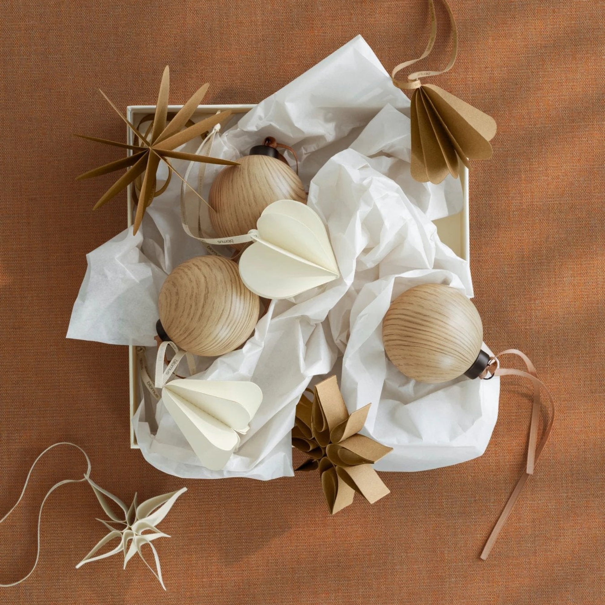 Decorative items including wooden balls and dried plants in a box on a brown textured surface