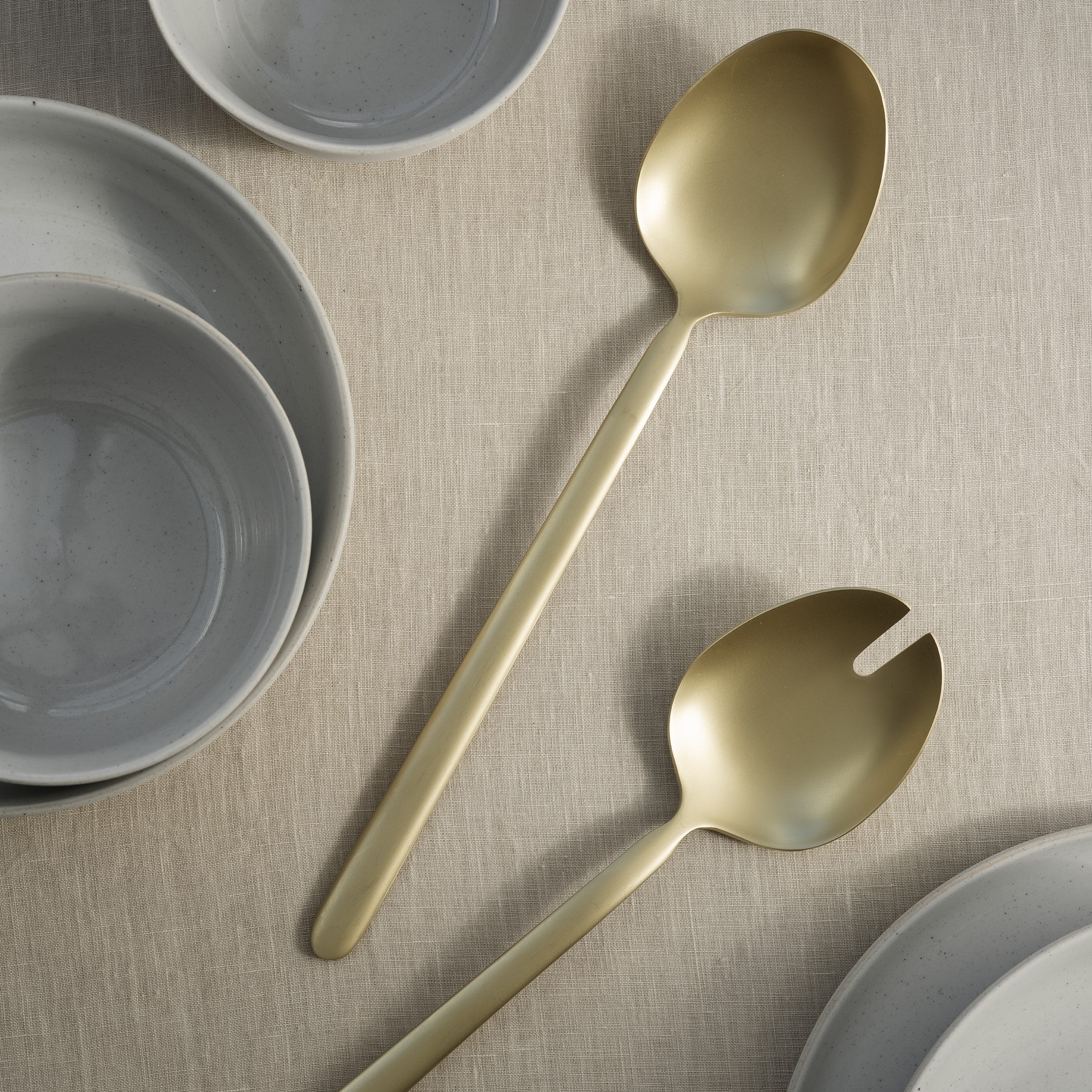 matte gold salad servers from blomus STELLA collection on burl wood table with dishes