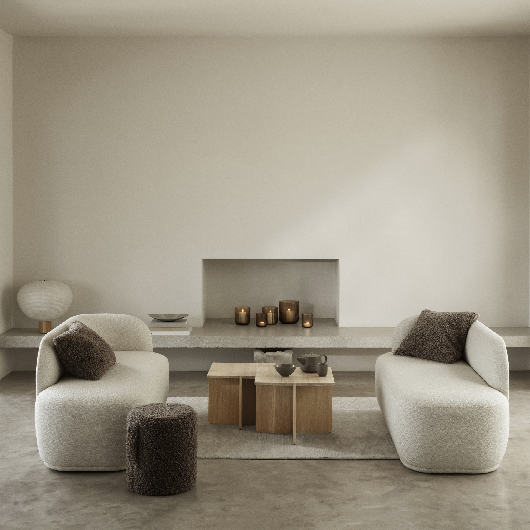 ENGAWA Tables in a living room setting in front of a modern fireplace containing VEN Candle Holders. Living room also contains couches and a TEDDY Pouf.