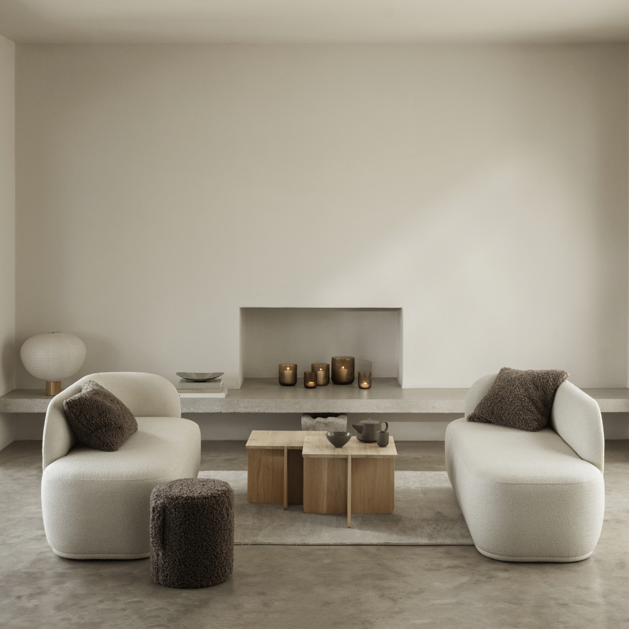 ENGAWA Tables in a living room setting in front of a modern fireplace containing VEN Candle Holders. Living room also contains couches and a TEDDY Pouf.