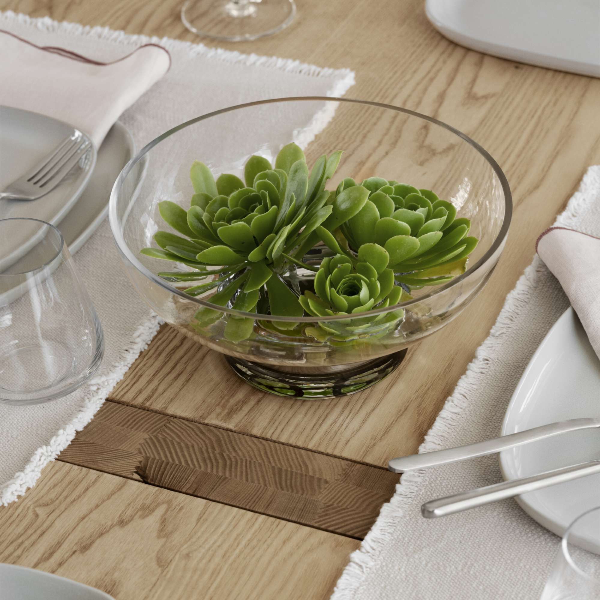MIYABI Glass Vase Low with succulent flowers inside placed on a wood table with dishes surrounding it.