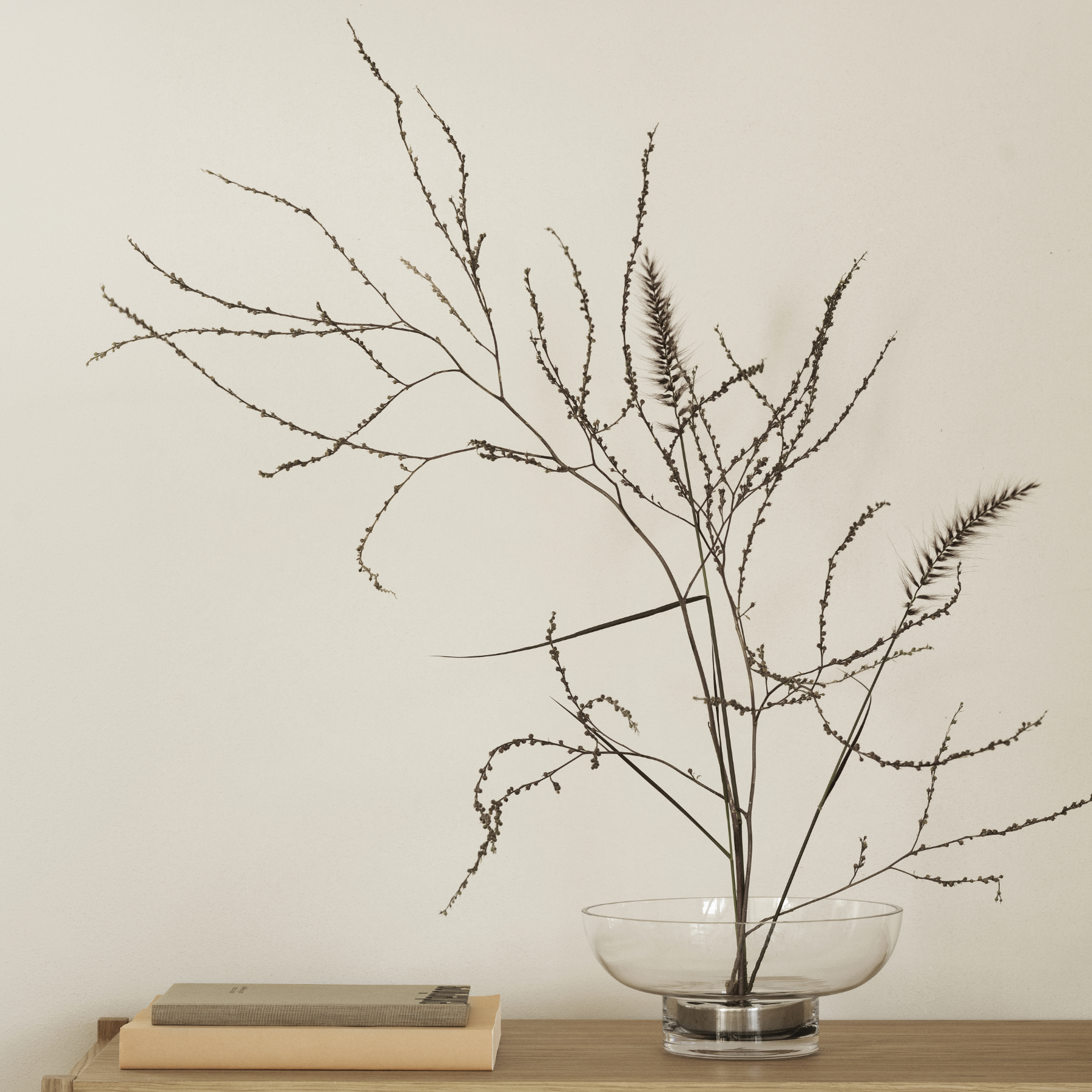 MIYABI Glass Vase containing branches sitting on a wood shelf with books placed beside it.