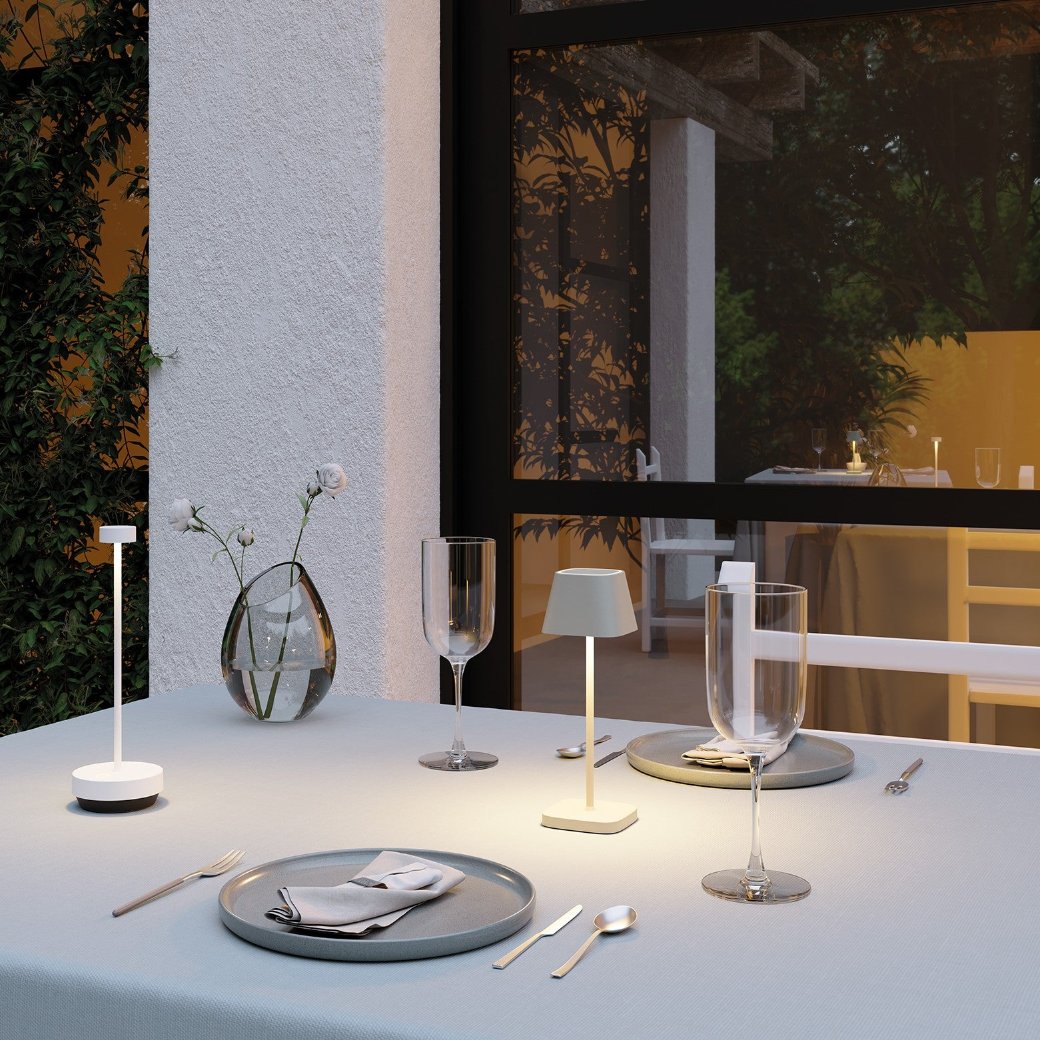 Elegant dining table set with plates and wine glasses lit by rechargeable table lights