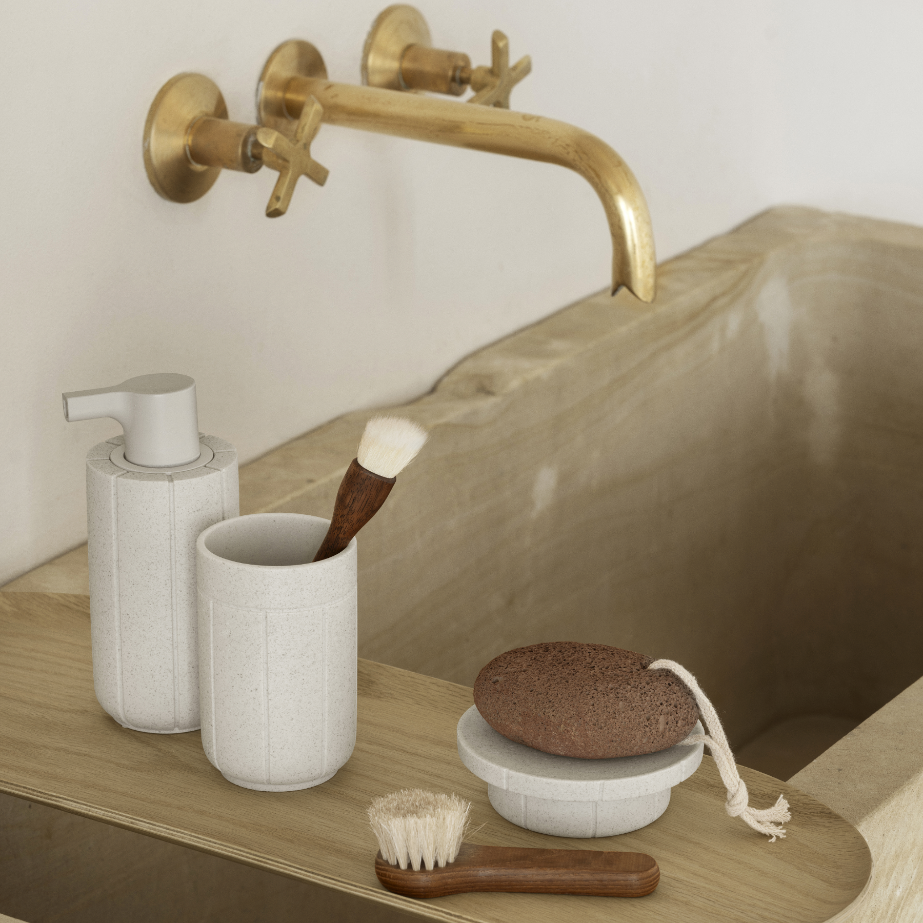 Bathroom sink with gold faucet, blomus KUA soap dispenser, tumbler and tray staged on a blomus BAKI wood tray.