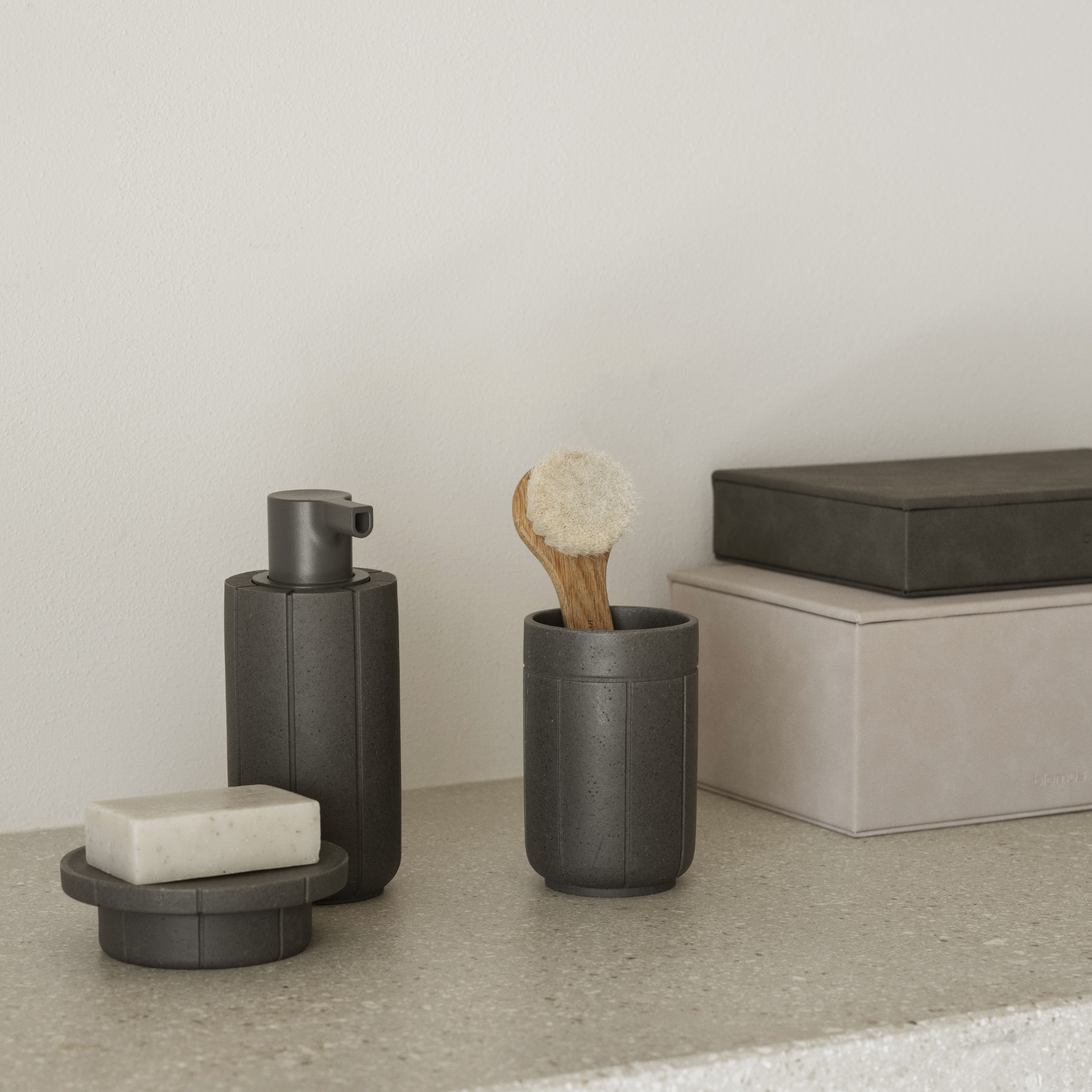 KUA Bathroom accessories including a soap dispenser, tray and tumbler on a counter with blomus SAHLA Jewelry Boxes to the side.