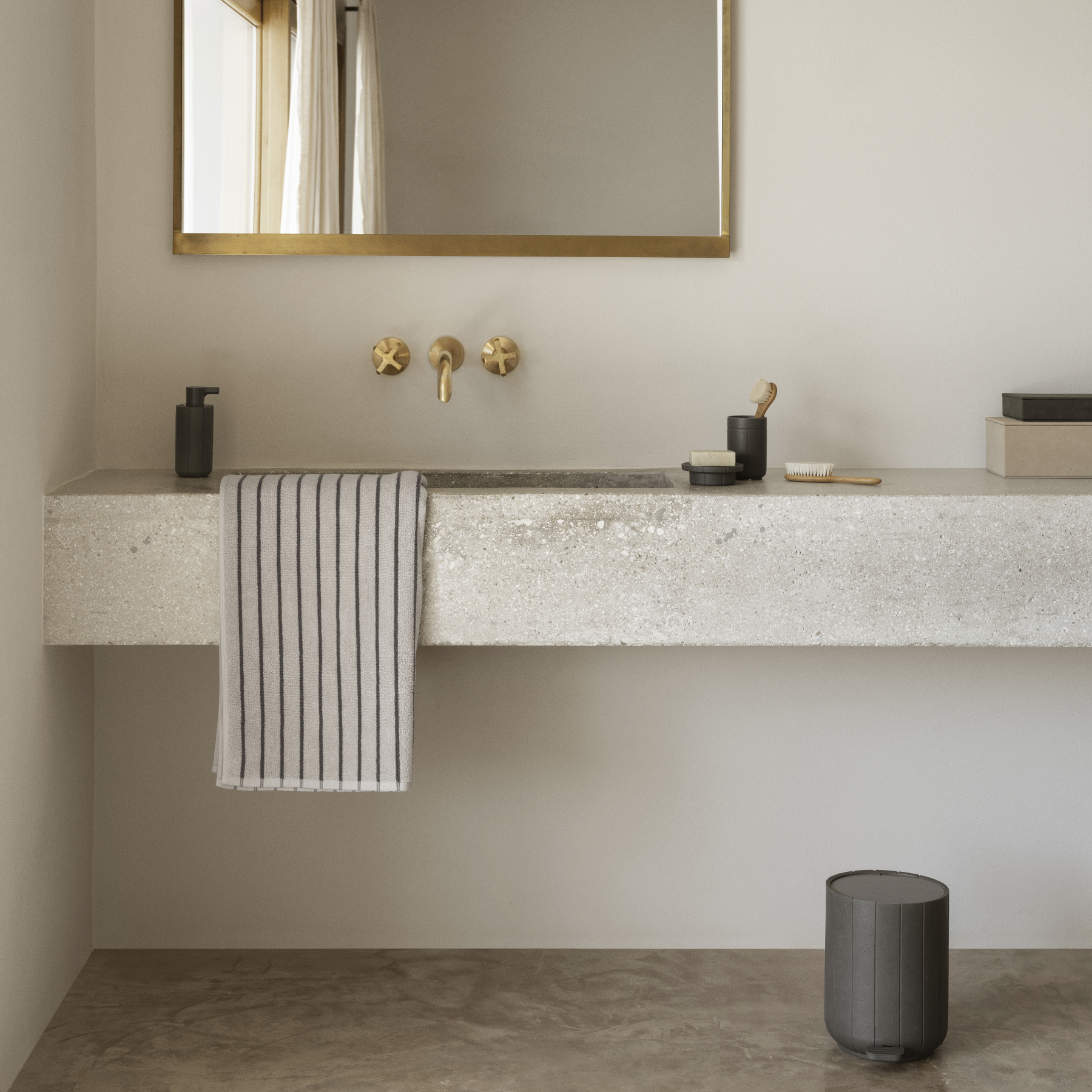 Modern bathroom with concrete vanity, gold fixtures, and a mirror.
