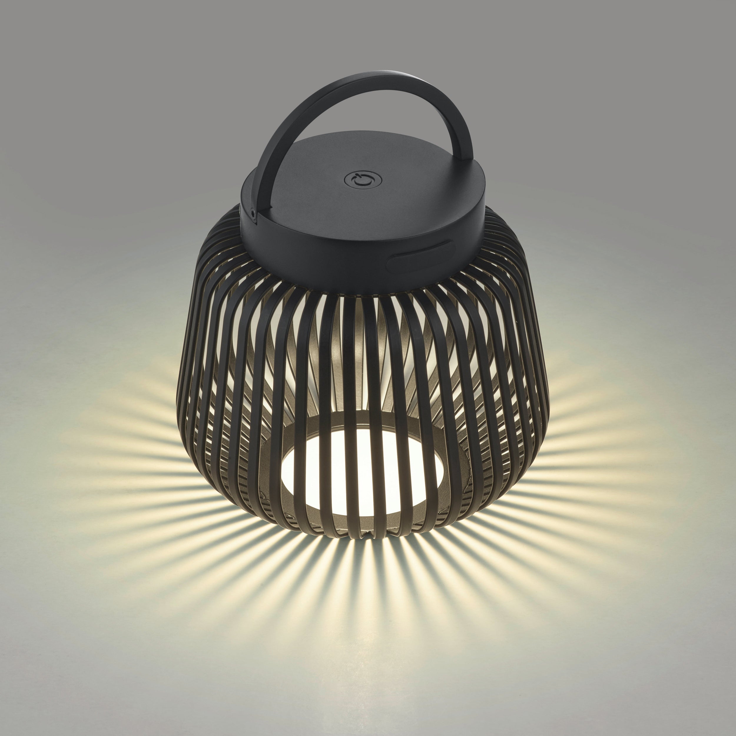 LITO Black lantern with a handle on a gray background, showing light reflection.