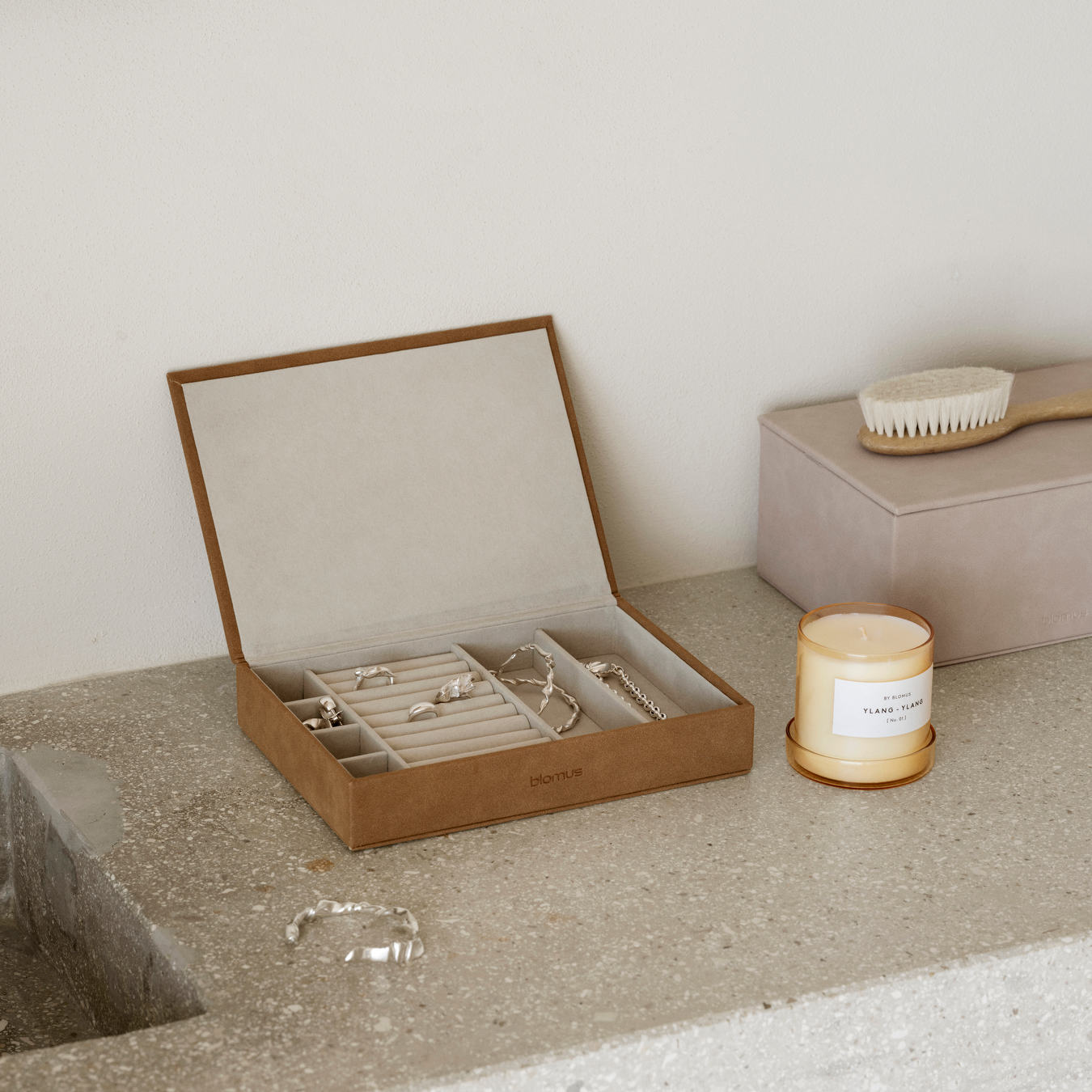 Open SAHLA Jewelry Box with jewelry and a SAHLA Large Jewelry Box closed on a concrete surface next to a blomus candle.