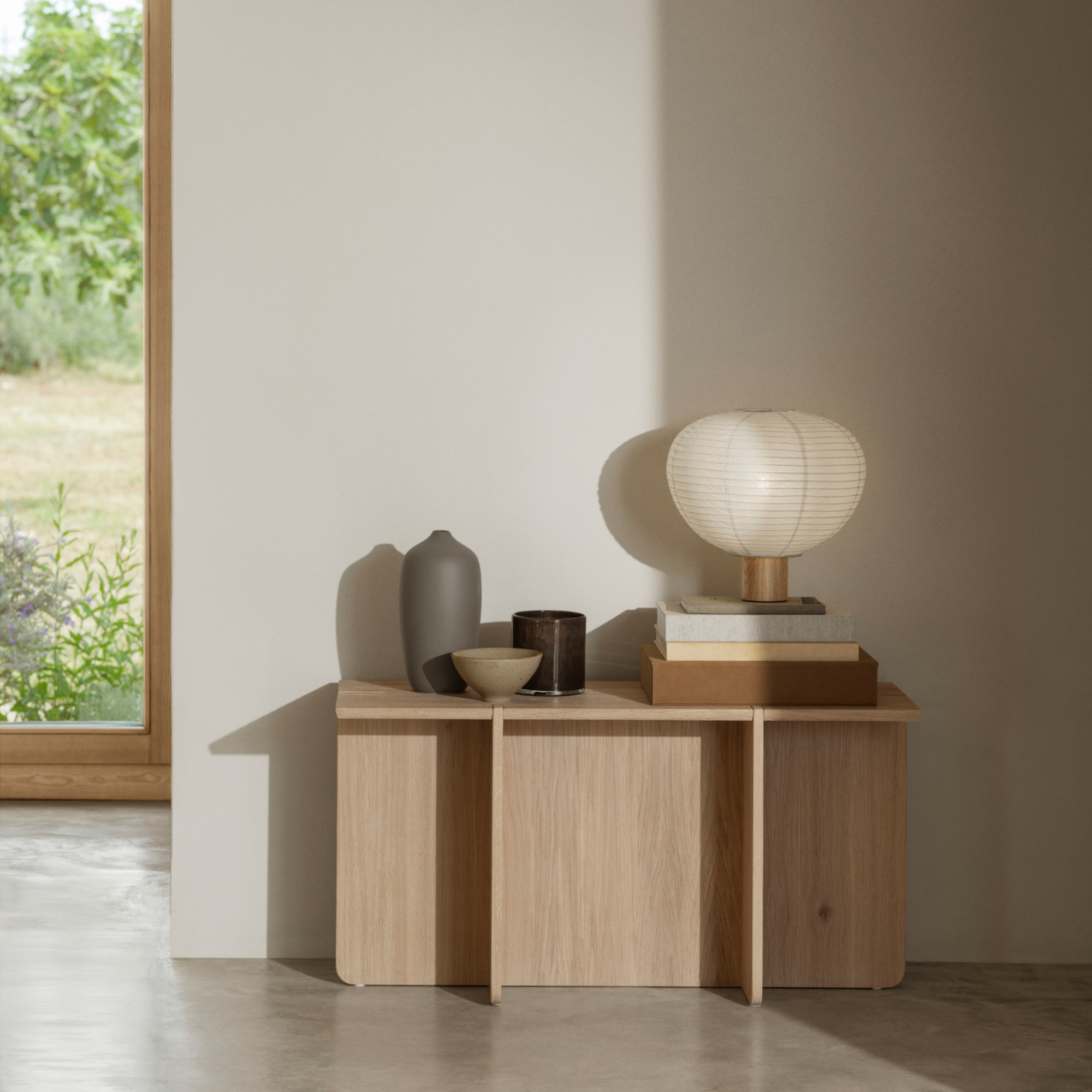 SAHLA Storage Box sitting atop an ENGAWA Bench with a lamp, vases, books and a bowl in a neutral room.