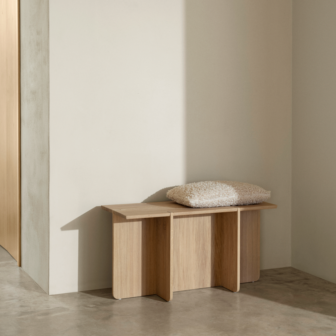 ENGAWA Bench with a pillow on top placed in an entry area of a home with concrete floor and neutral wall color.
