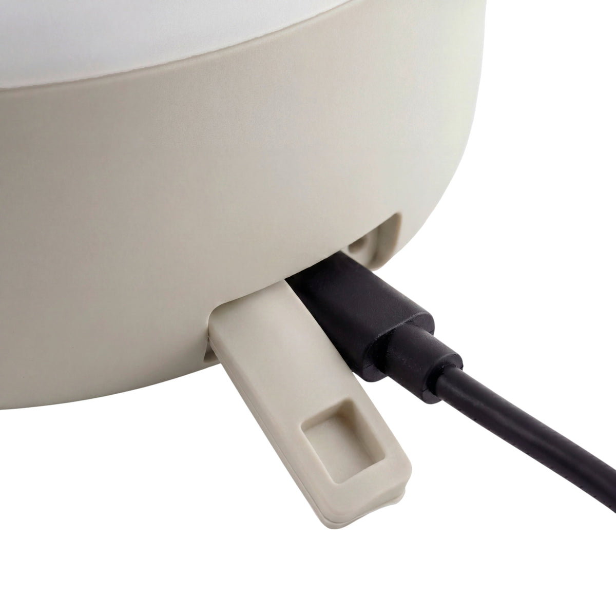 Close-up of a silk grey CALMA LED lantern being charged with a power cord shown on a white background.