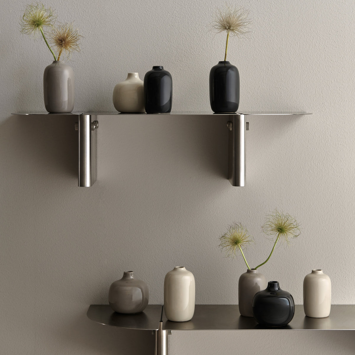 Modern wall-mounted metal shelves in a neutral interior setting, styled with CEOLA ceramic vases with and without flowers .