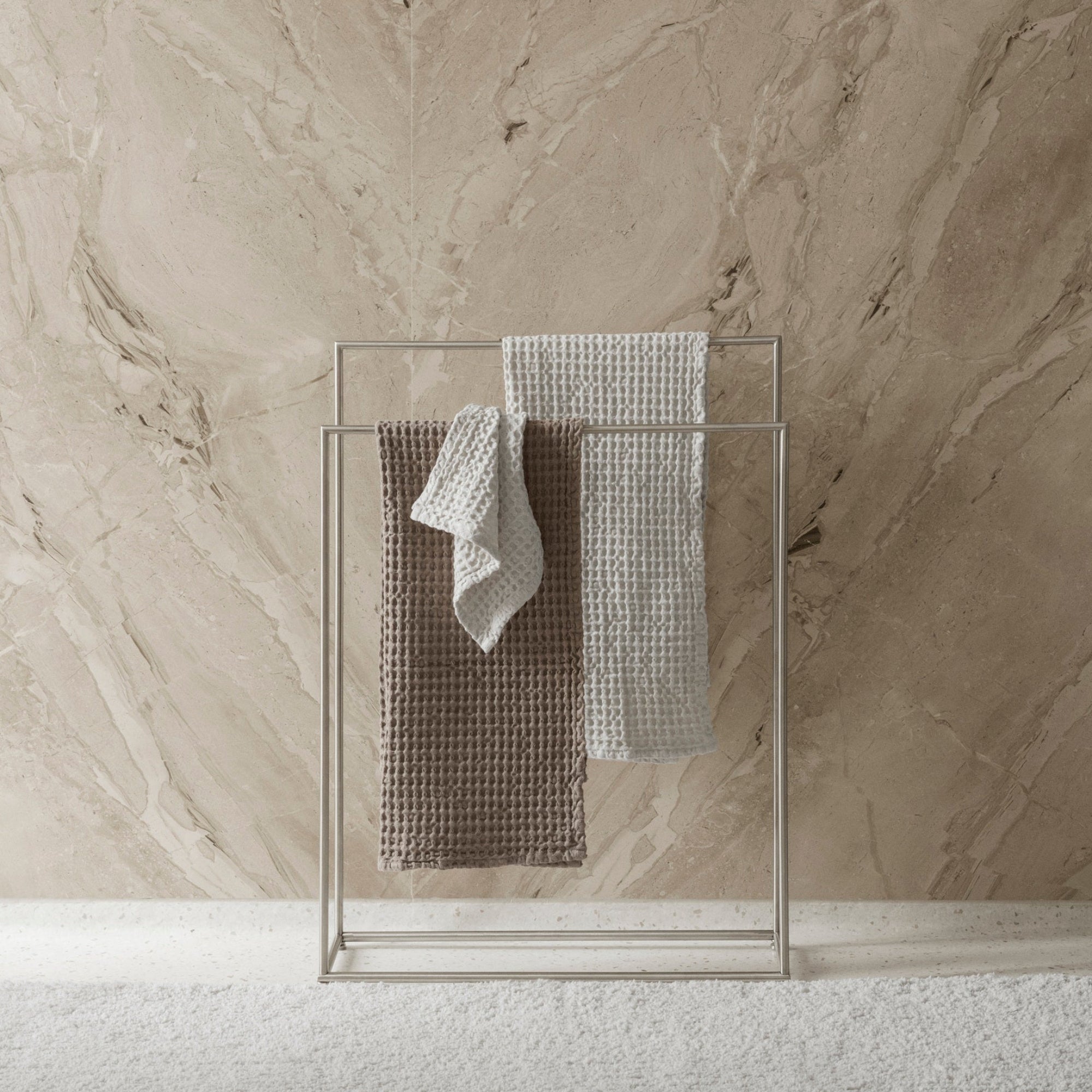 Towel rack with towels against a marble wall