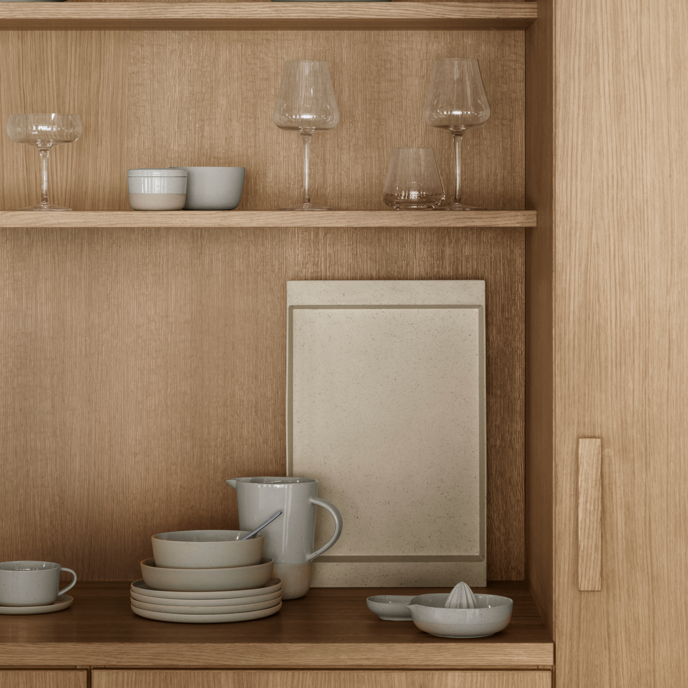 casually arranged collection of blomus SABLO ceramic tableware pieces in a minimalist white oak cabinet