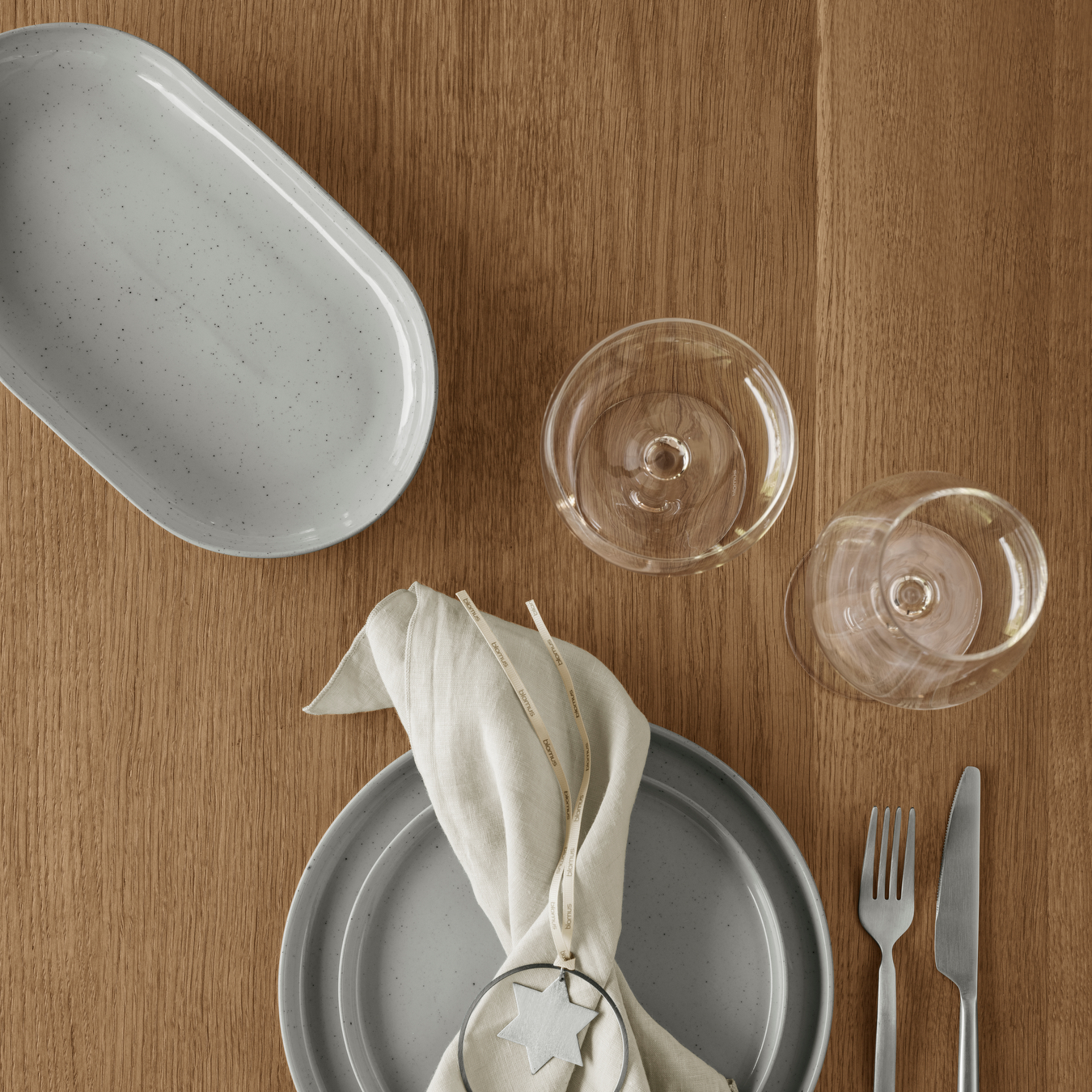 blomus SABLO stoneware collection in Cloud white speckled glaze arranged in a minimalist place setting featuring the deep serving platter on an oak table