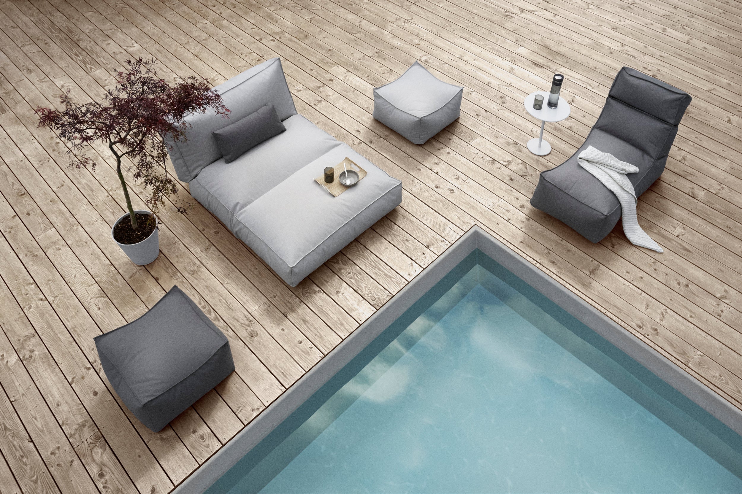 Outdoor furniture set by a pool on a wooden deck