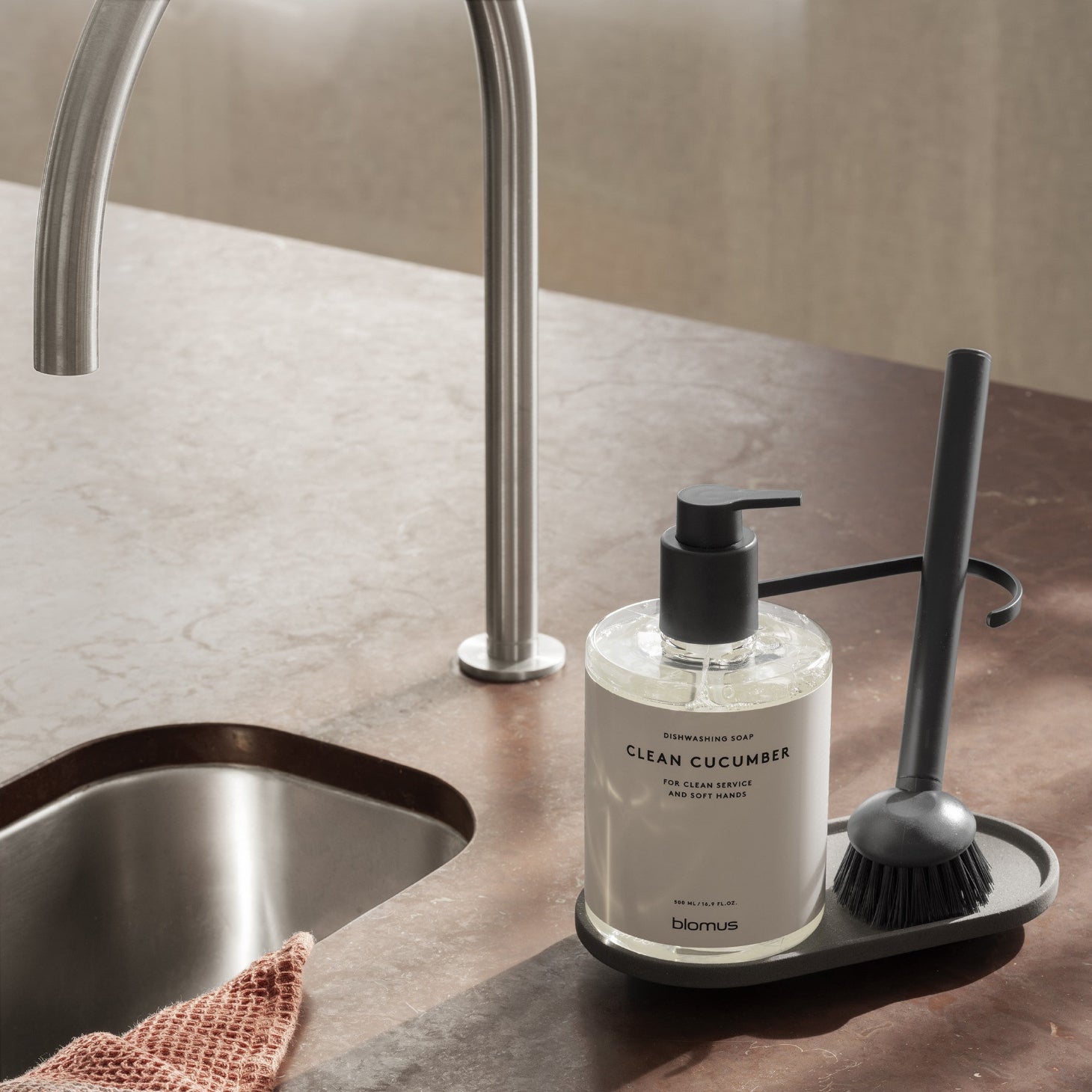 blomus DHUVA ceramic kitchen sink organizer on red marble countertop by sink