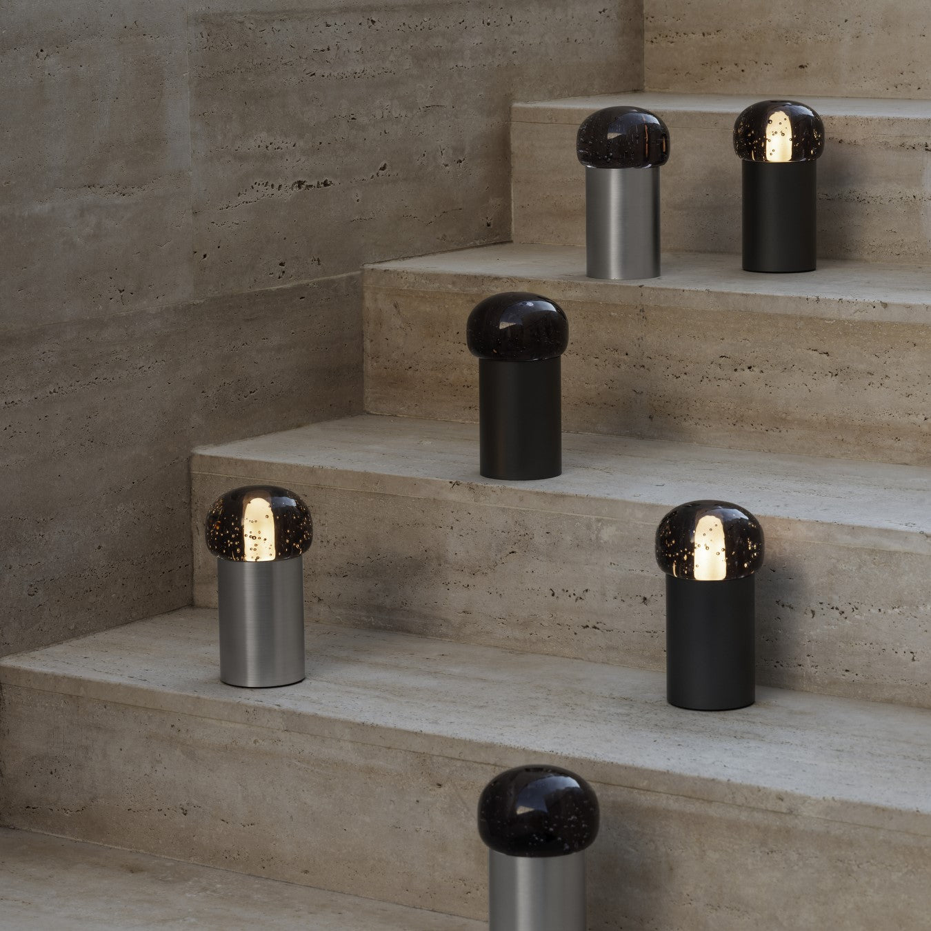 Rough concrete staircase with many small lamps with metal cylindrical base and glass globe top