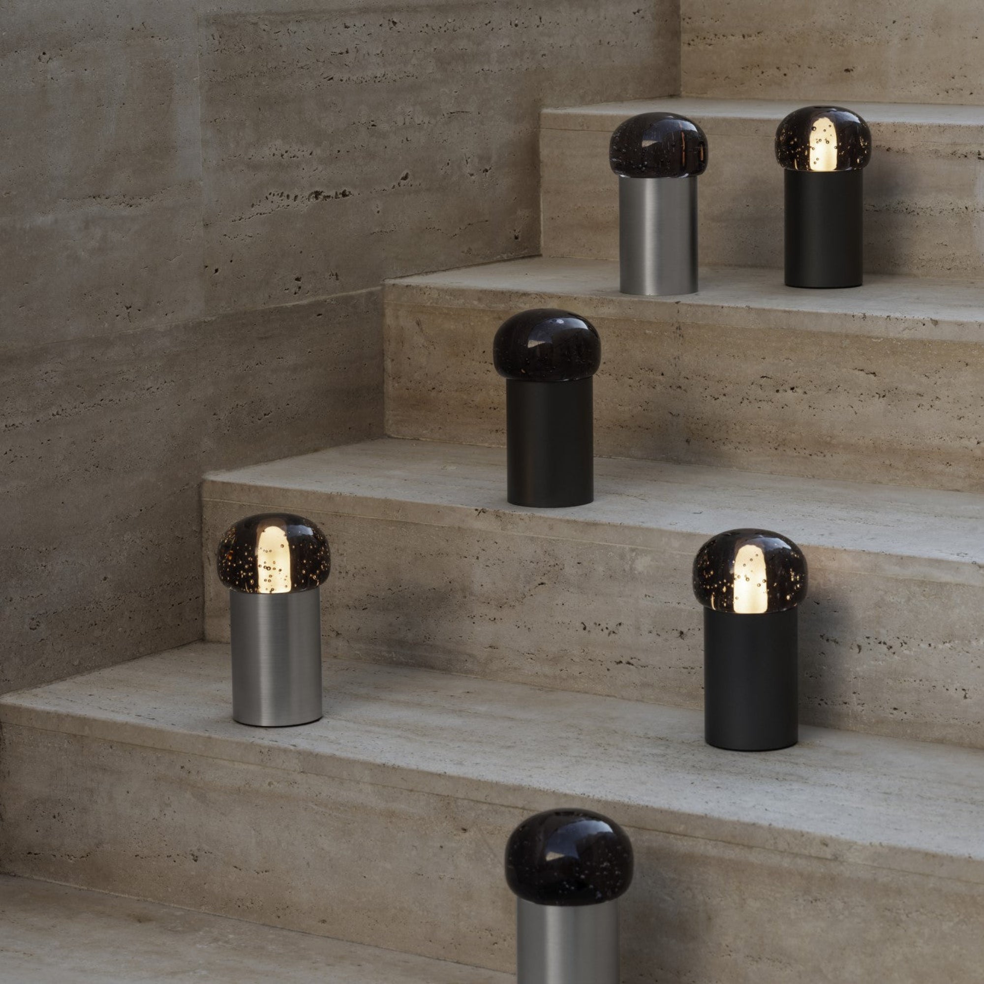 Rough concrete staircase with many small lamps with metal cylindrical base and glass globe top