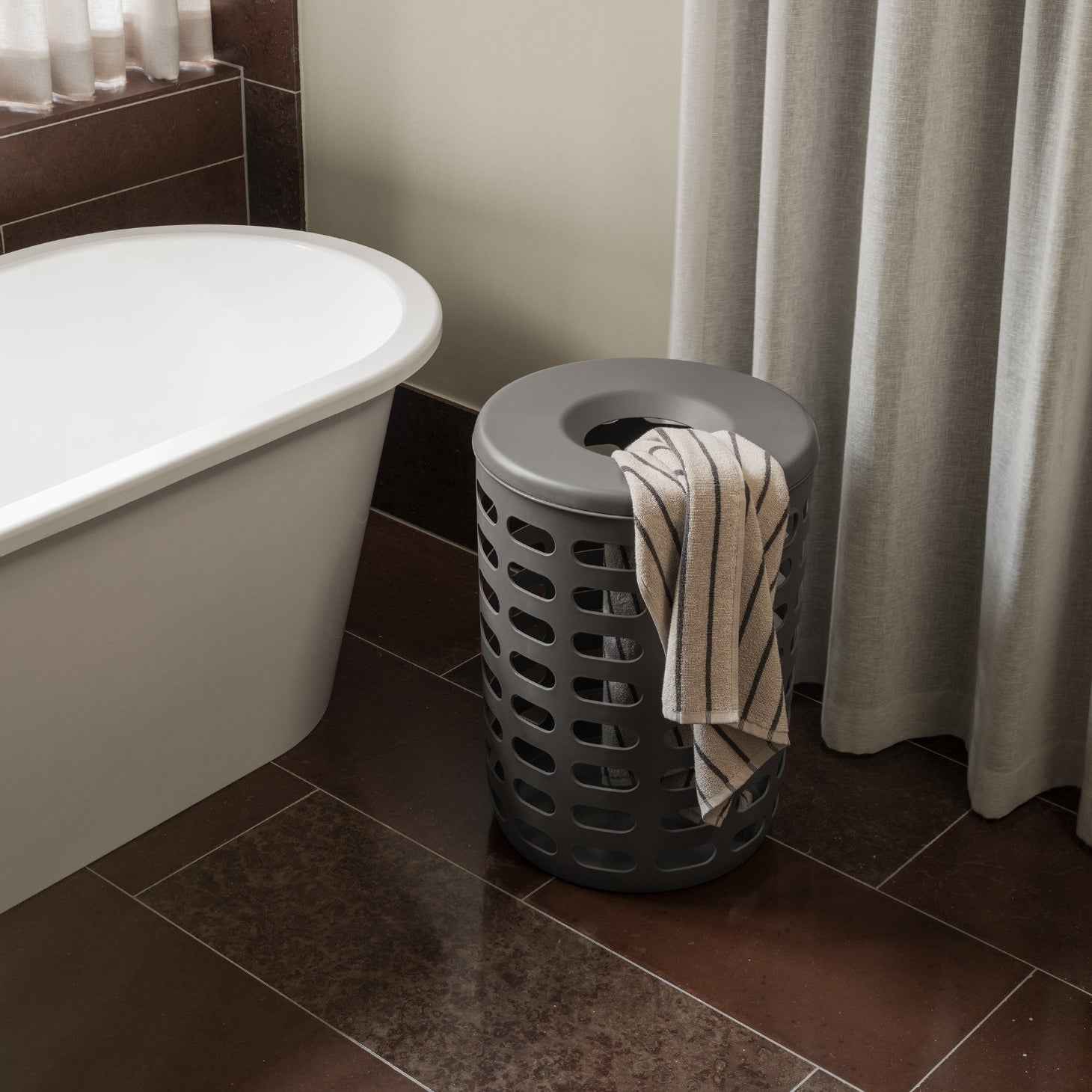 blomus KORIE decorative plastic laundry with lid and striped towel in a bathroom with marble floors