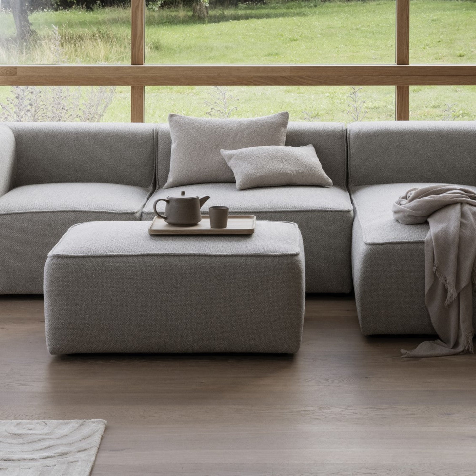 tea served on a rectangular natural oak tray by a cozy modern couch 