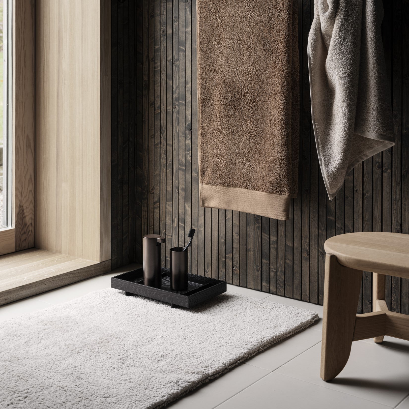 Bathroom setting with RIVA Towels hanging on hooks against wall.