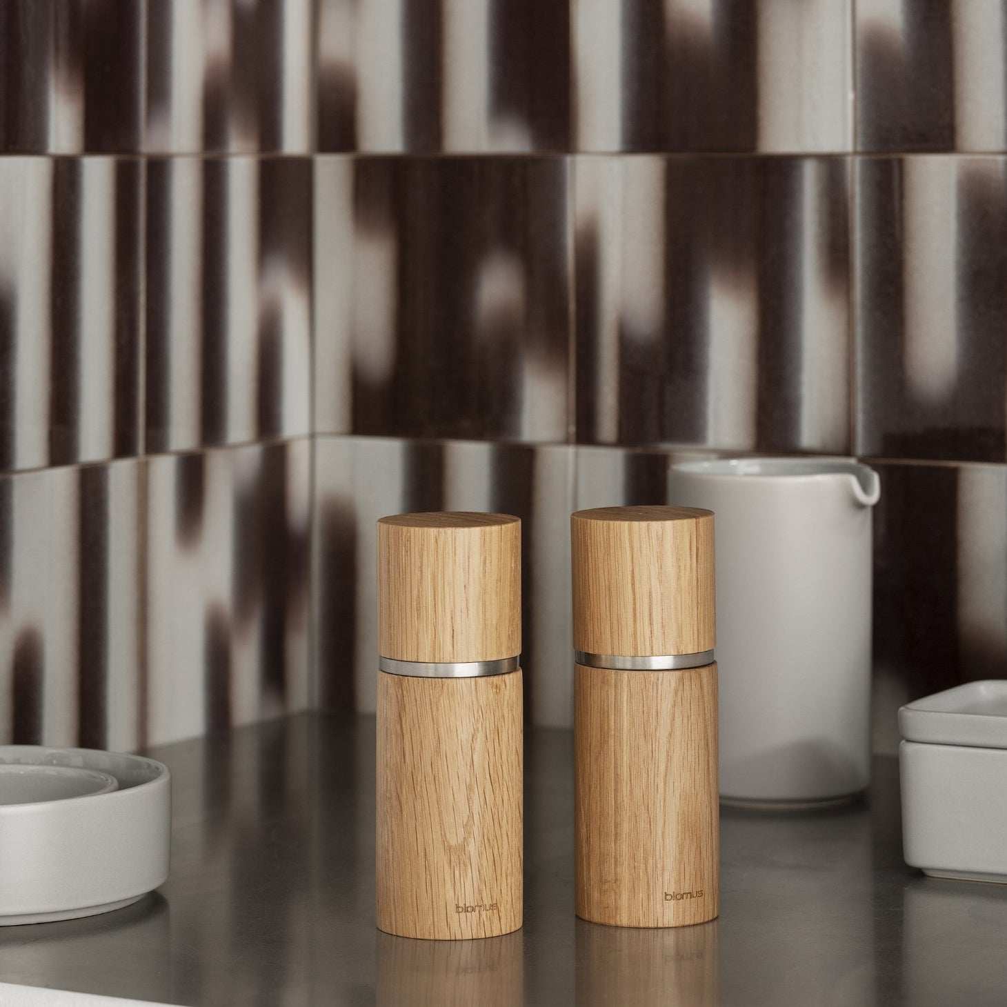 modern kitchen counter displaying PEPE oak spice grinders by blomus