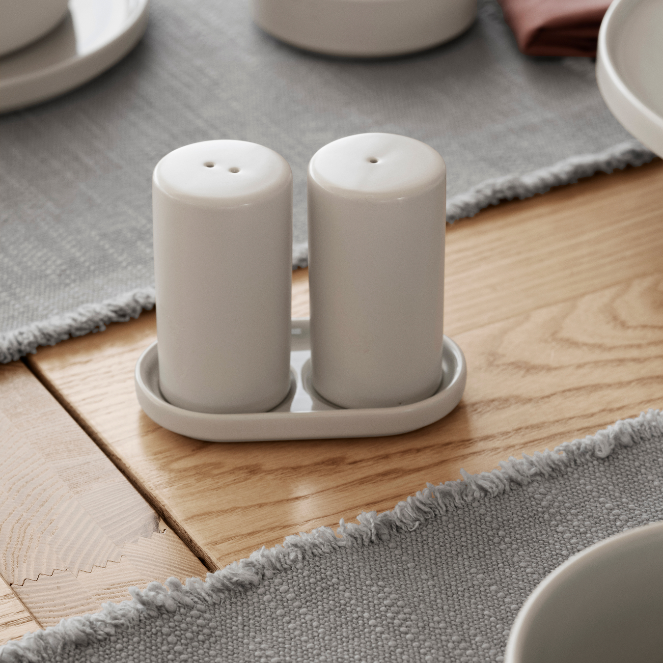 PILAR Moonbeam Salt and Pepper Shaker Set on a wooden table with gray placemats.
