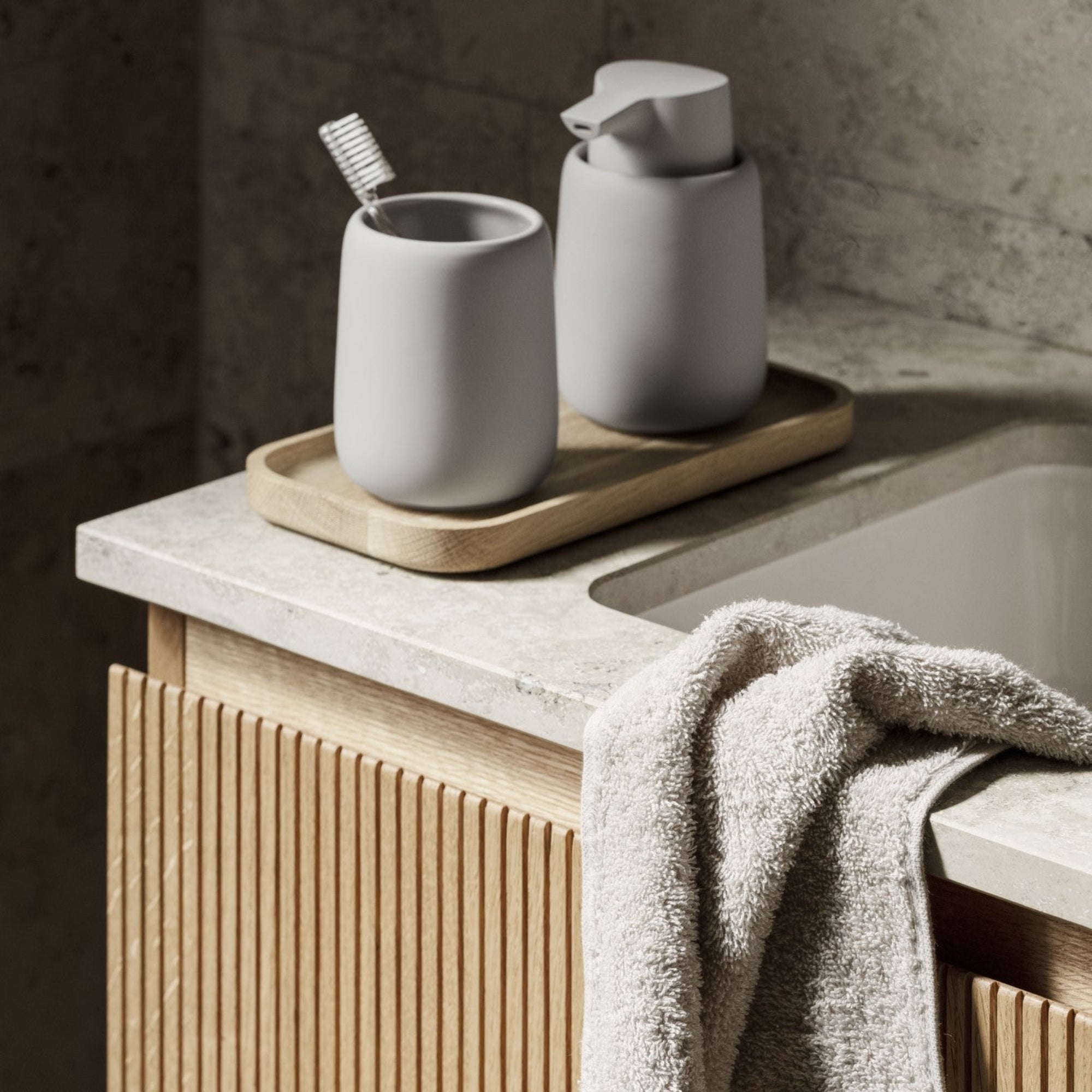 blomus OKU small oak tray in natural finish supporting bathroom accessories by a sleek contemporary sink
