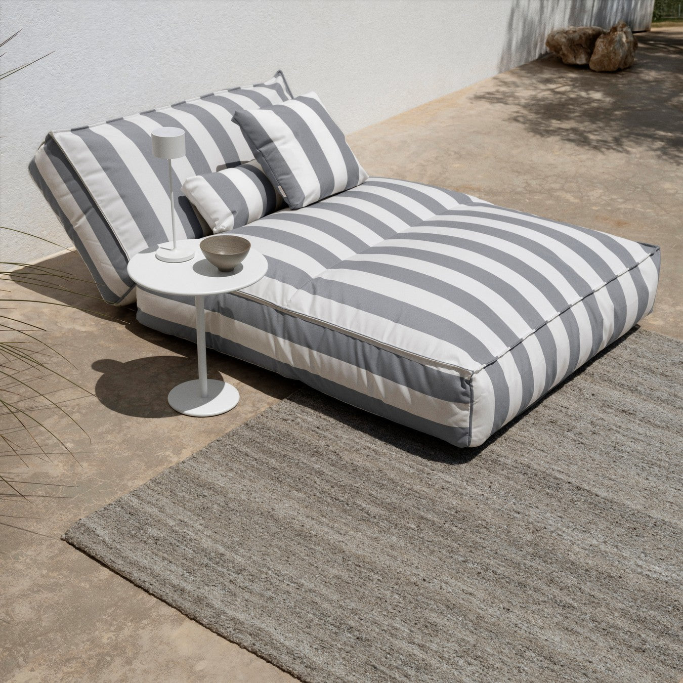 Gray and white striped outdoor sofa with cushions on a patio