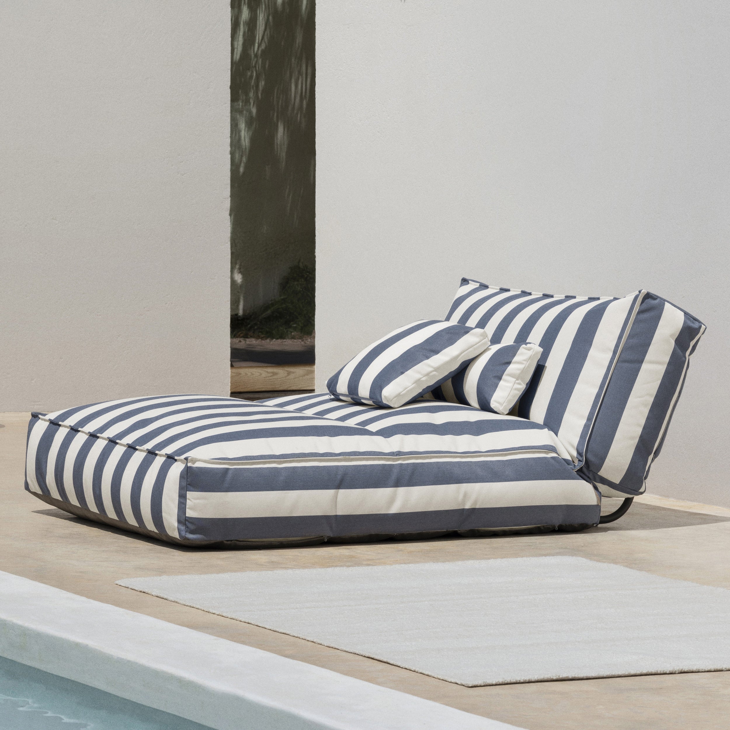 Striped outdoor lounge chair on a patio with a neutral background