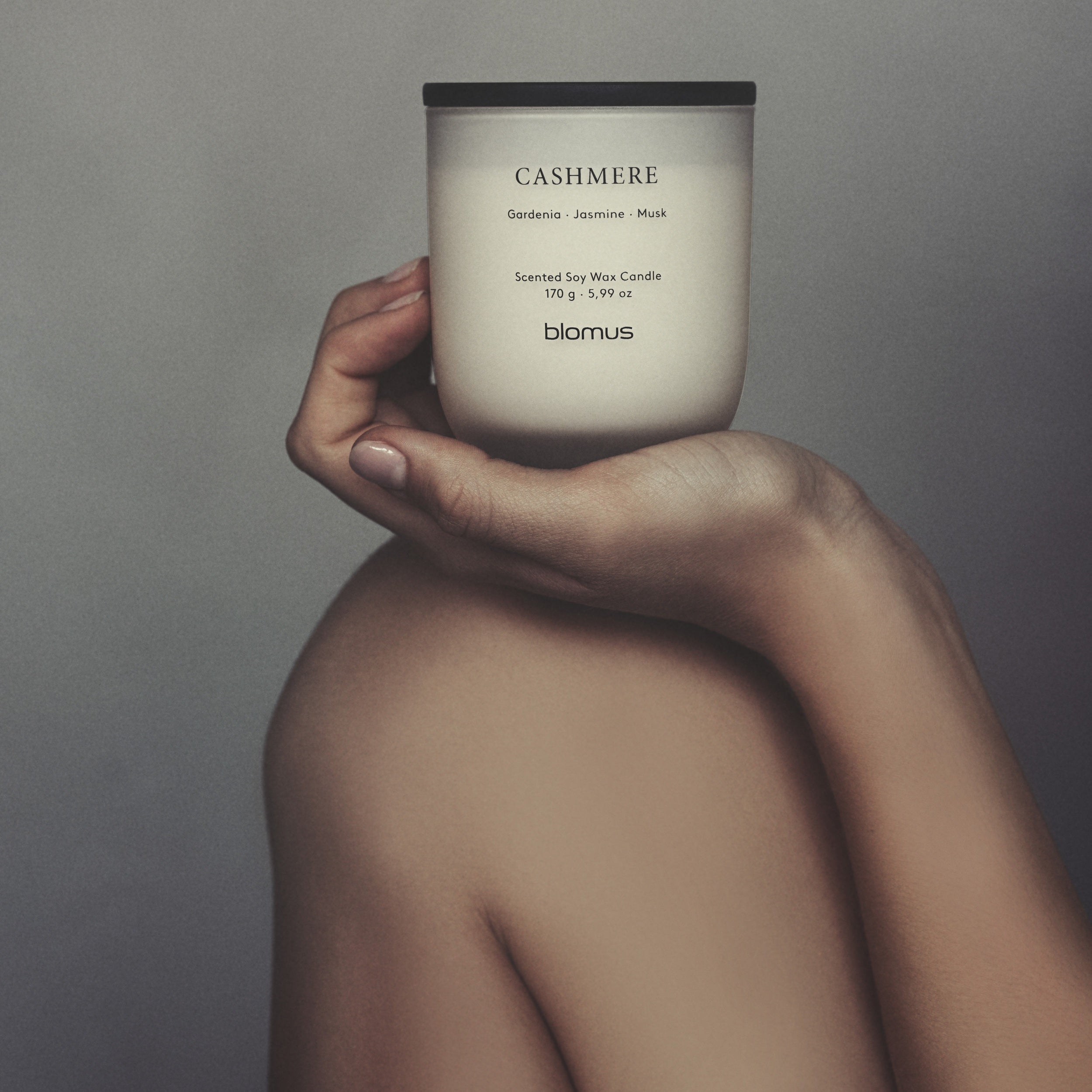 Model holding Cashmere scented candle atop her bare leg.