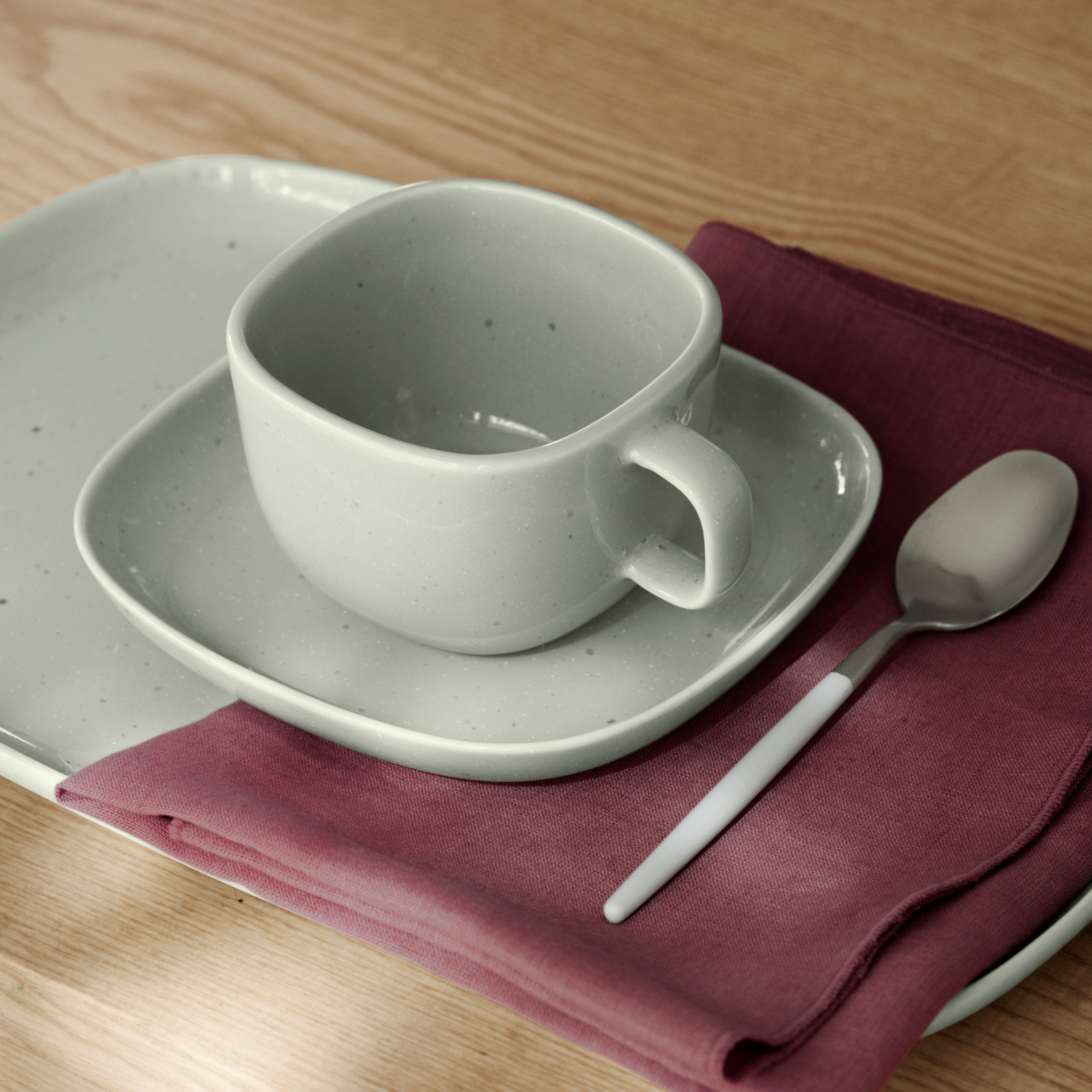 Up close image of VAHLO Coffee Cup and Saucer on a VAHLO Plate with napkin and spoon on a wood table.