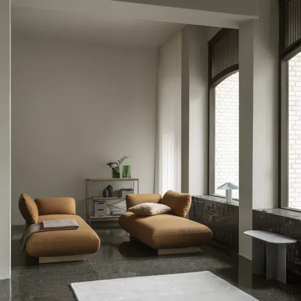 Modern living room with brown lounge chairs and large windows.