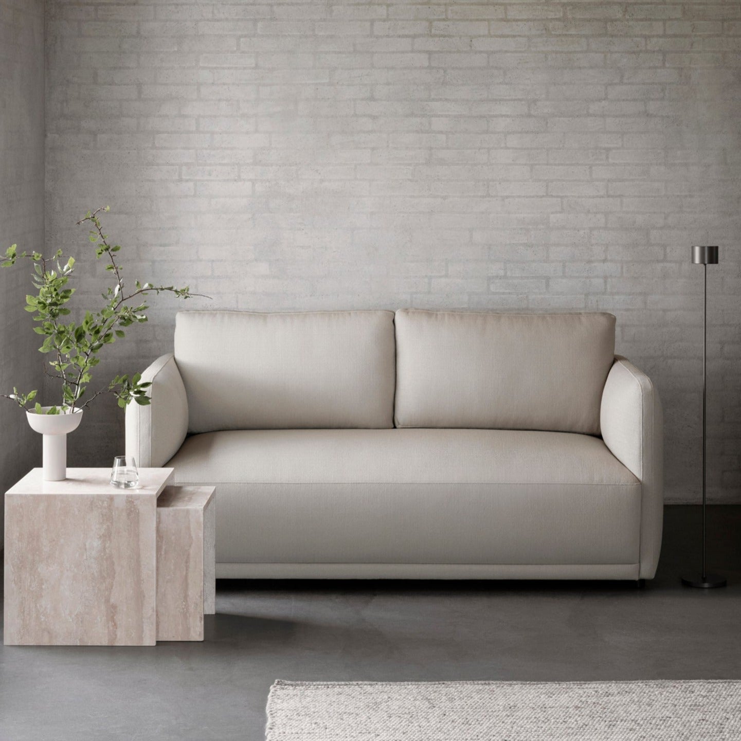 Simple sitting area with marble table, leather couch, and rechargeable floor lamp against a white brick wall