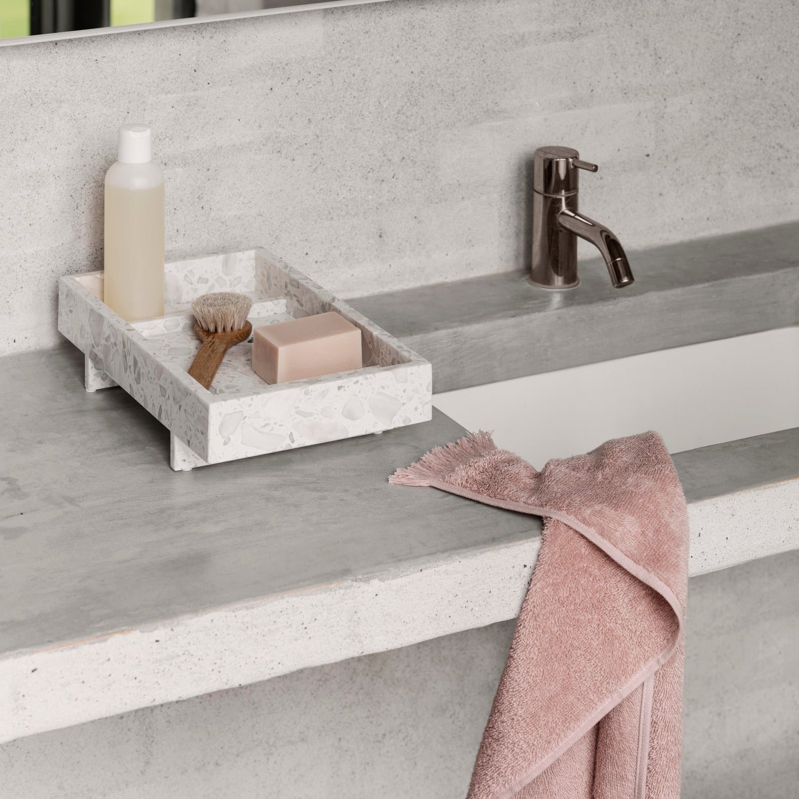 pink cotton terry cloth hand towel on a concrete sink