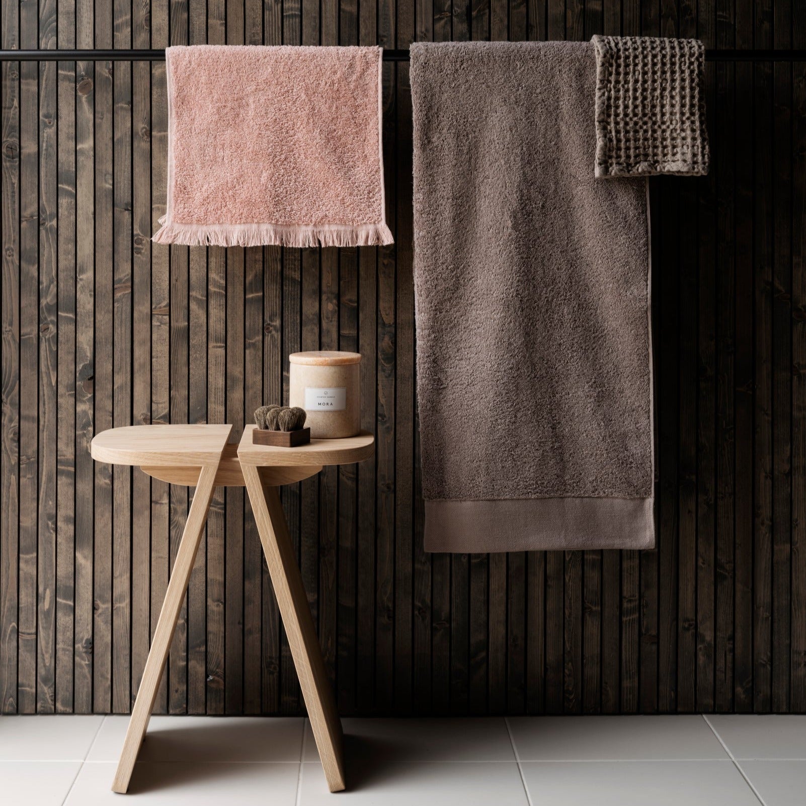 Organic cotton bath towels hanging against a wooden wall