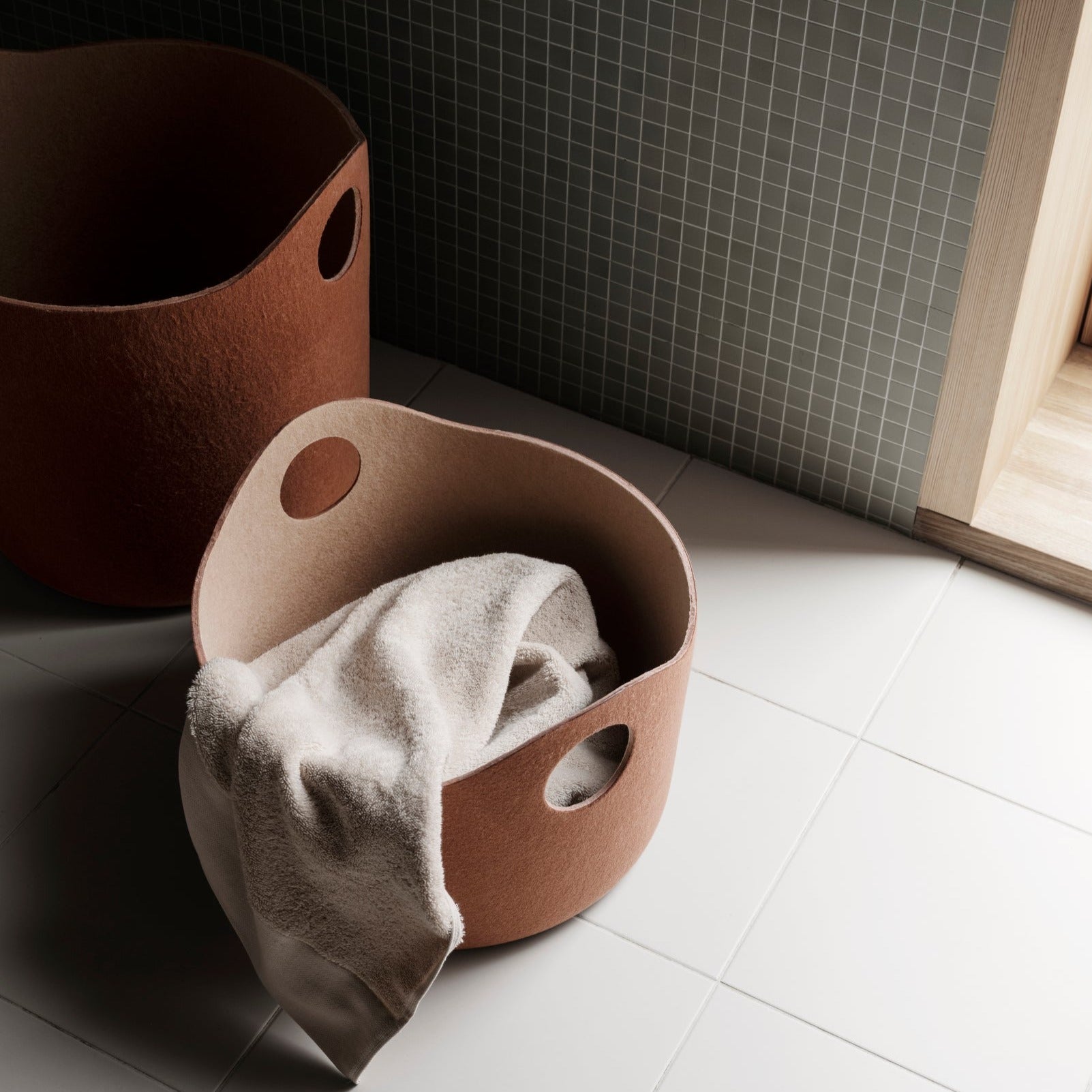 understated tile bathroom with blomus TIGGY felt storage basket holding a towel