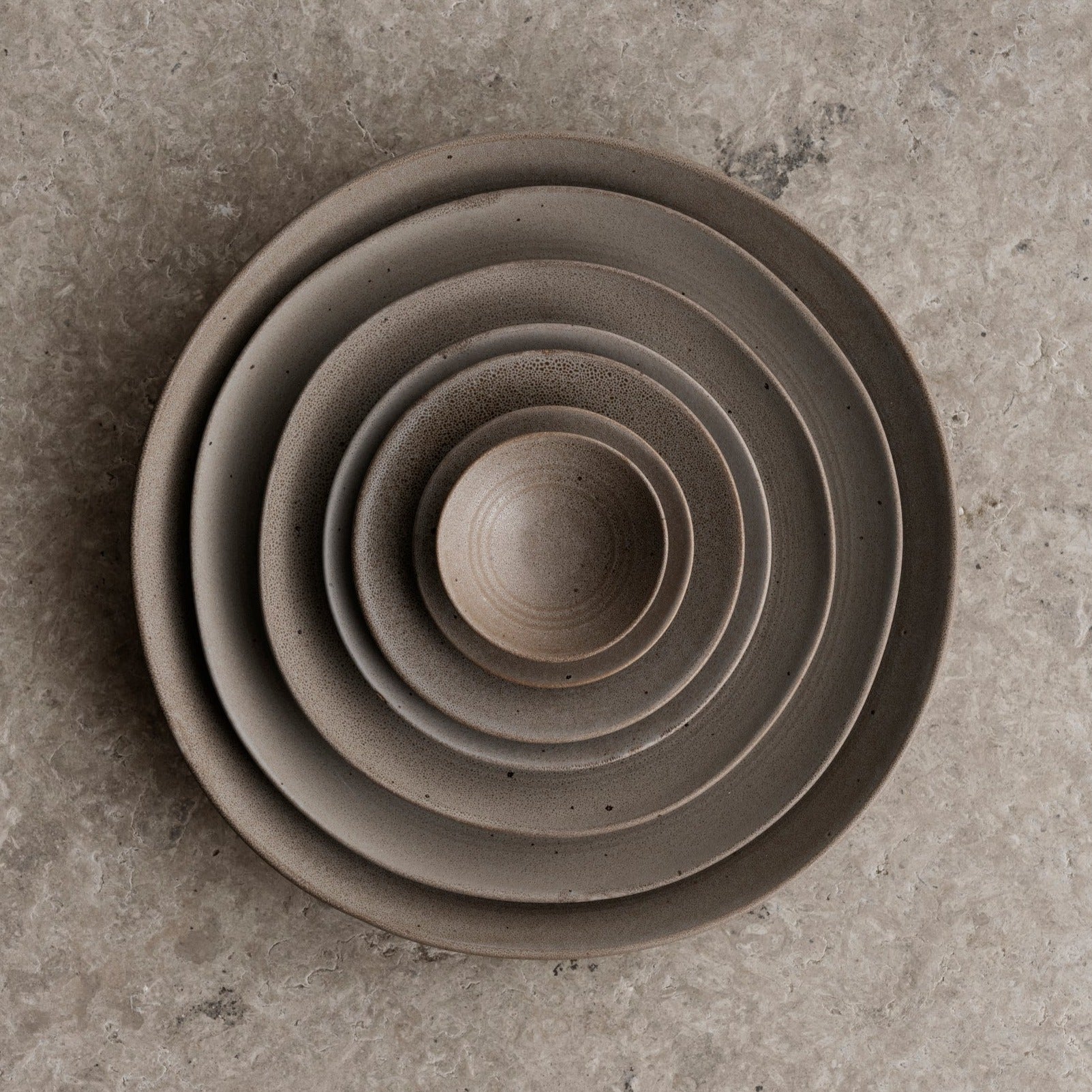 KUMI Stoneware Bowls in Fungi color  matte glaze all sizes stacked within each other on a stone surface