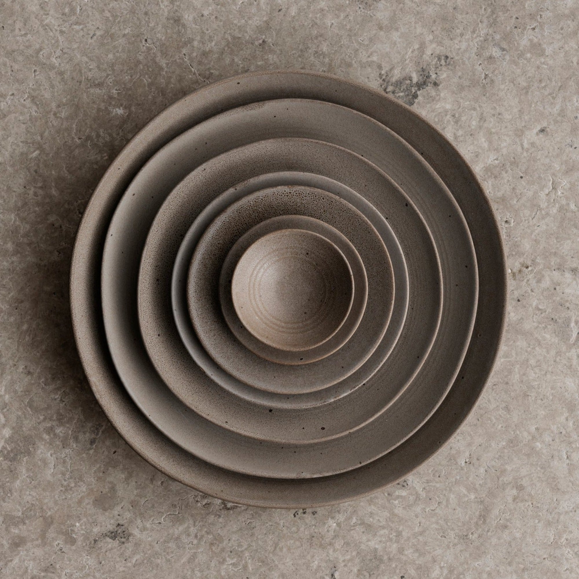 KUMI Stoneware Bowls in Fungi color  matte glaze all sizes stacked within each other on a stone surface