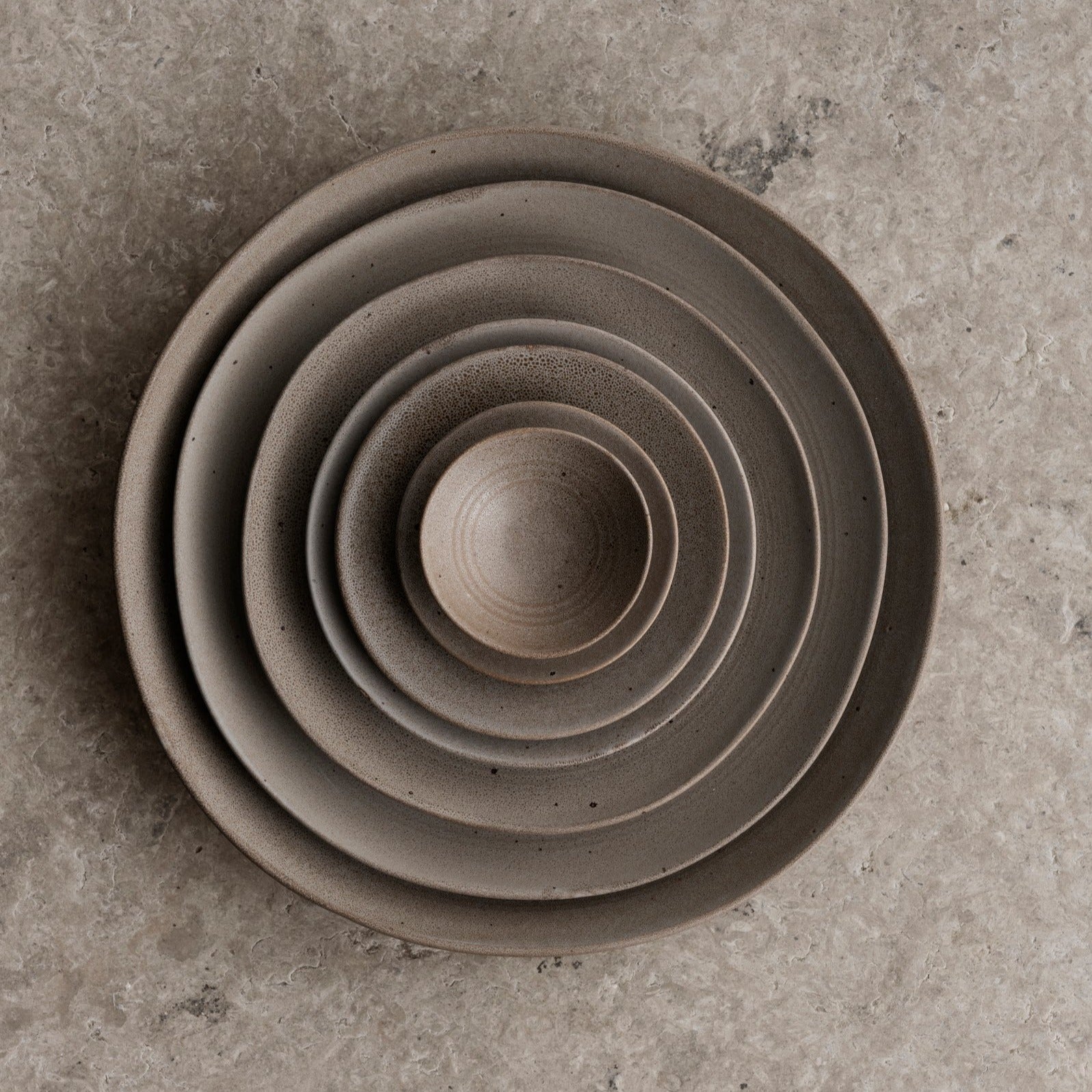 KUMI Stoneware Fungi Matte Glaze Bowls stacked inside one another on textured stone surface