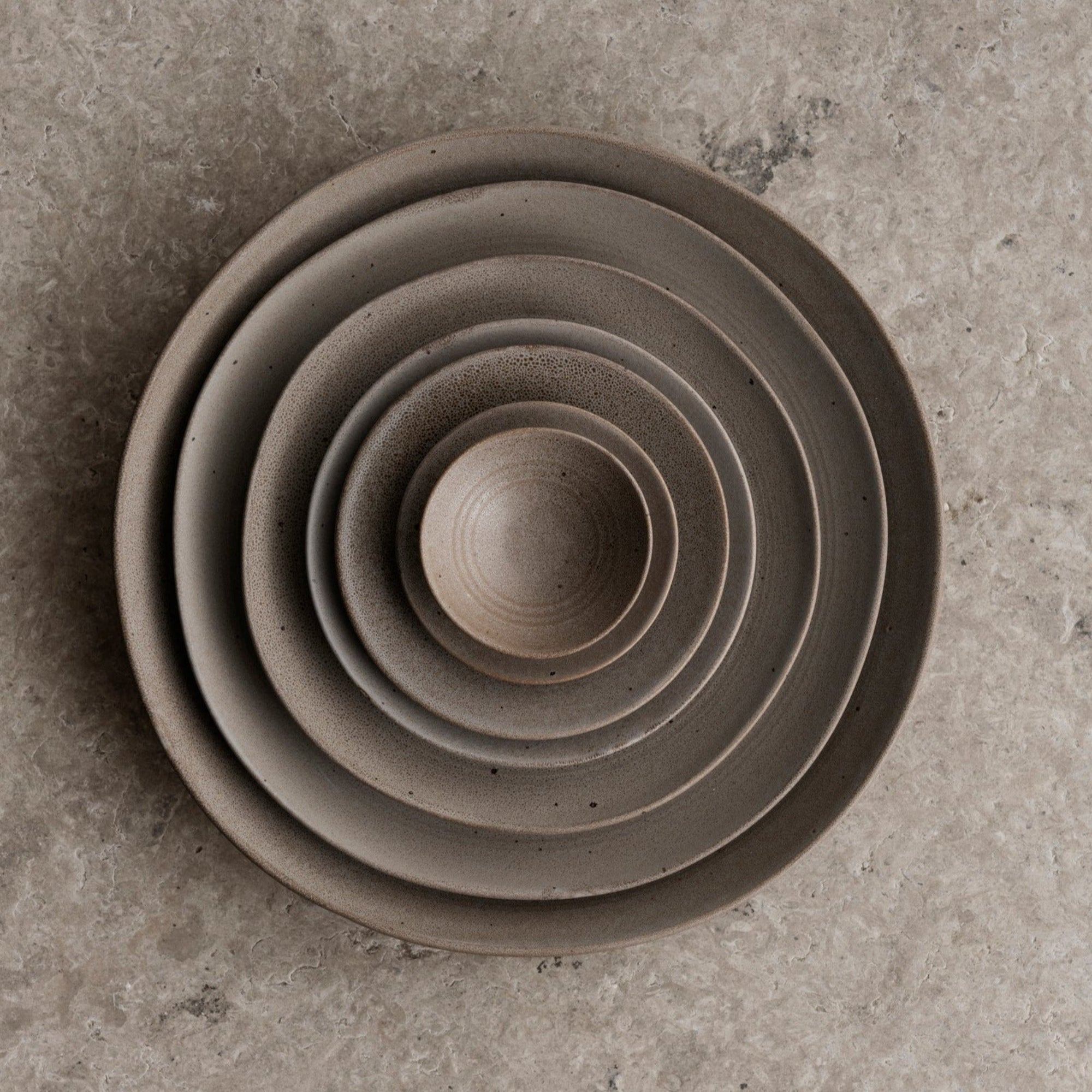 KUMI Stoneware Fungi Matte Glaze Bowls stacked inside one another on textured stone surface