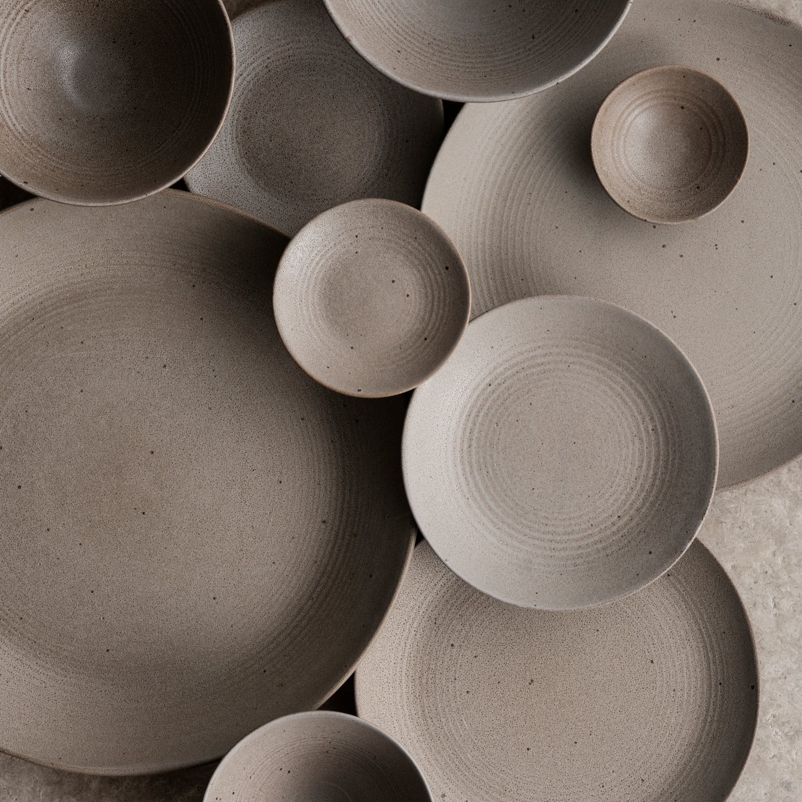 Close-up of blomus KUMI stoneware plates and bowls in Fungi beige layered in a chic lifestyle setting