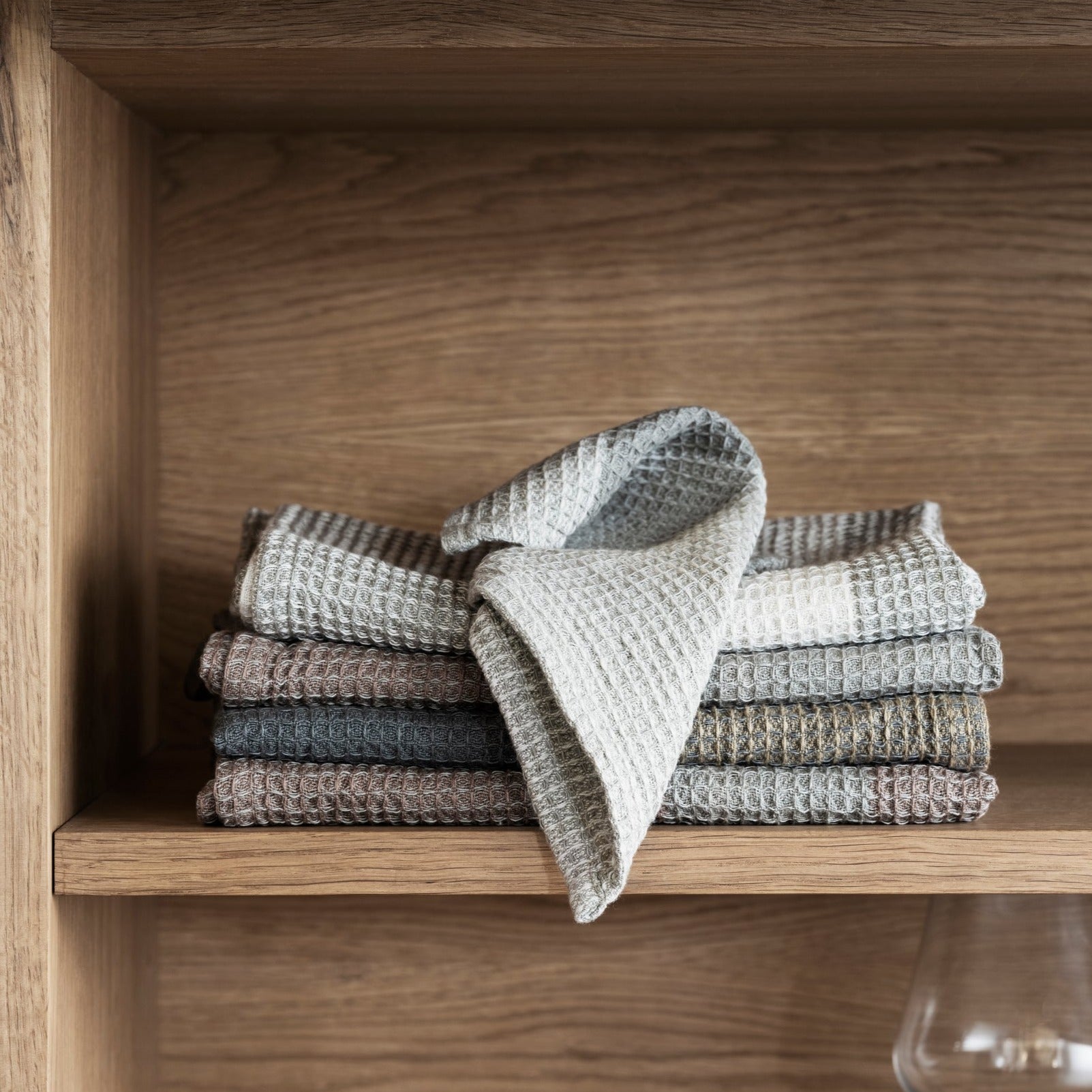 blomus GANO cotton waffle tea towels folded casually in a wooden cabinet