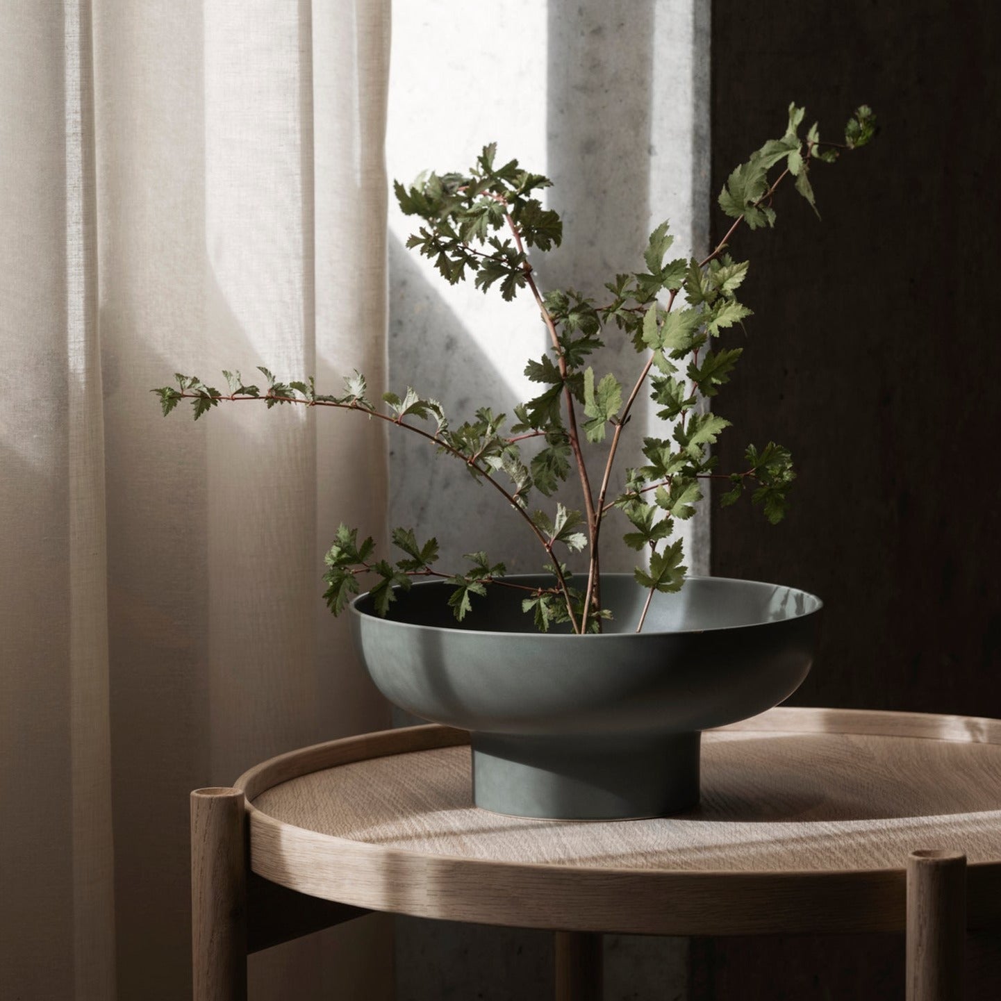 modern wooden side table with green MIYABI vase in front of a window with natural light