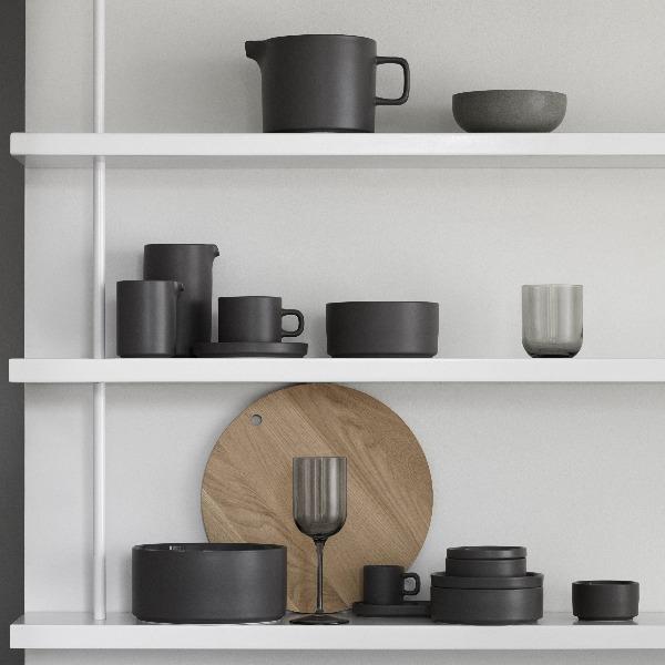 Scandinavian inspired design blomus PILAR dinnerware with matte pewter exterior stacked upon minimalist white shelves