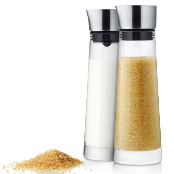 MACCHIATO glass creamer and sugar set next to a mound of granulated sugar 